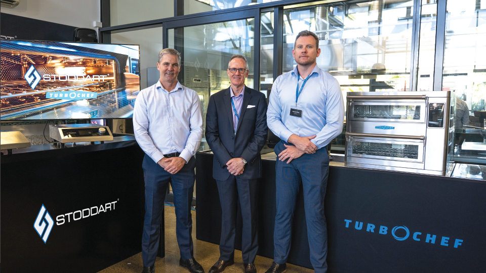 Three men in business wear standing between Stoddart and TurboChef ovens at a product showcase