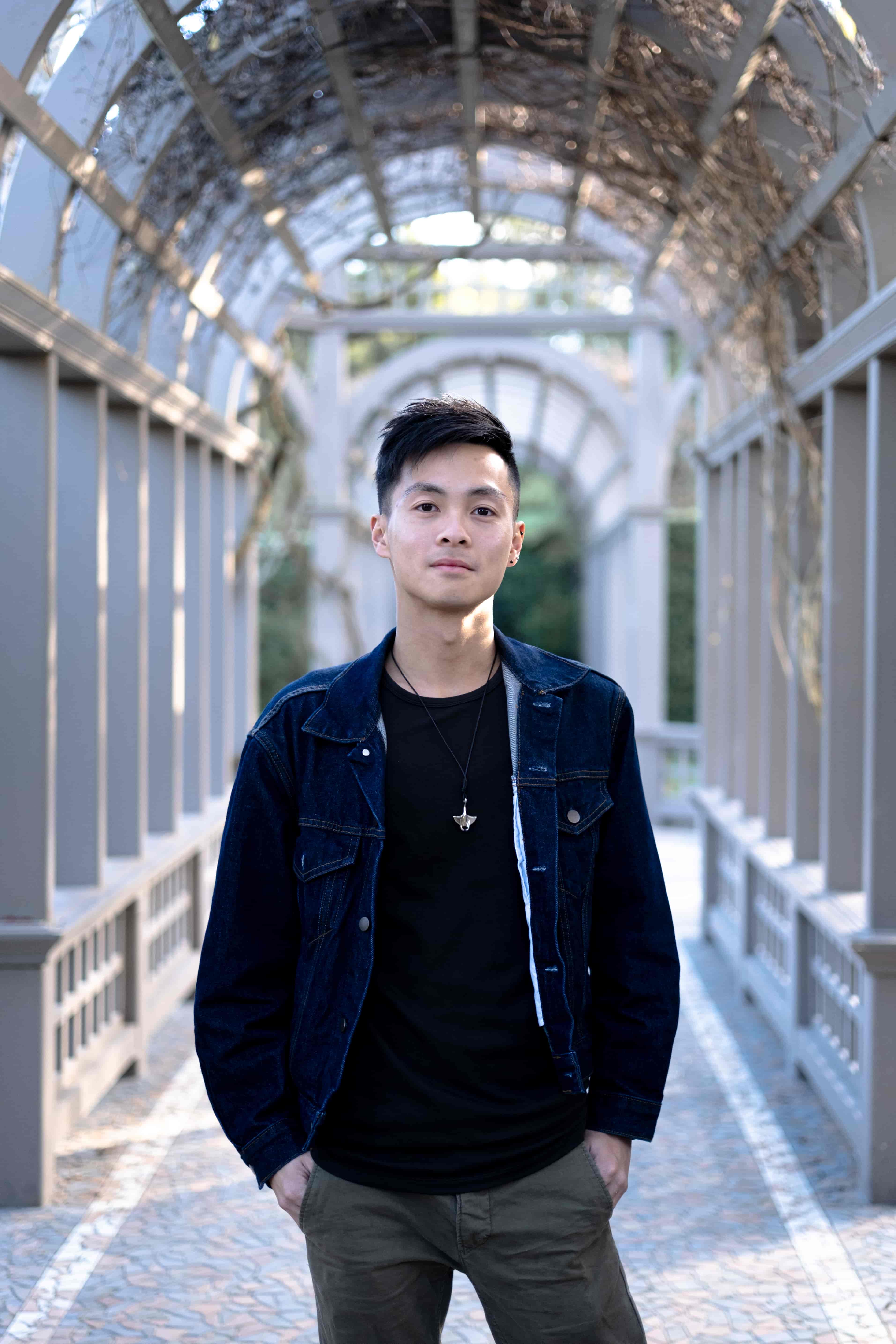 Man in a dark denim jacket standing in a long white timber pergola walkway, Hamilton Gardens