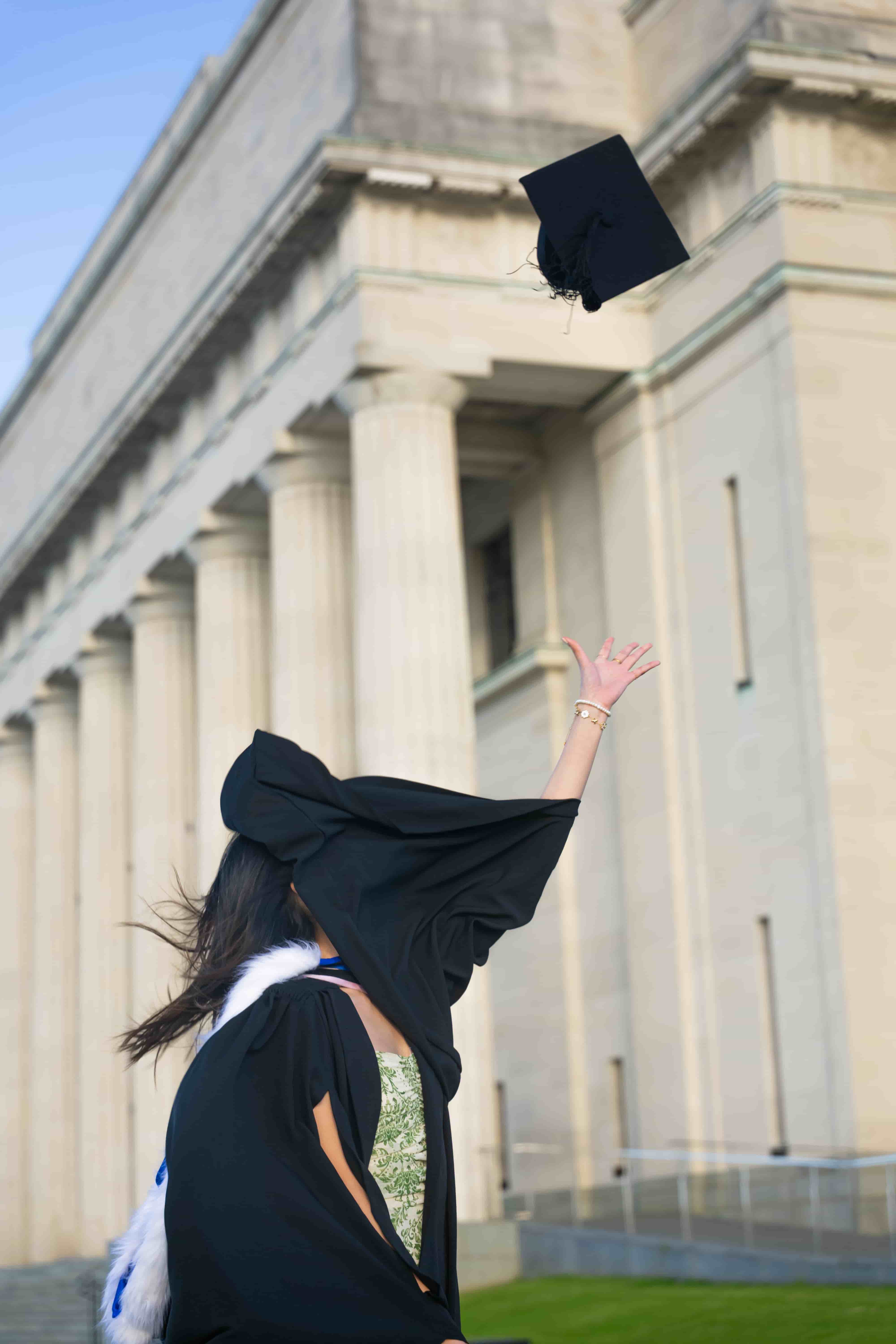 Graduation cap flying above Ruby with Auckland War Memorial Museum behind her