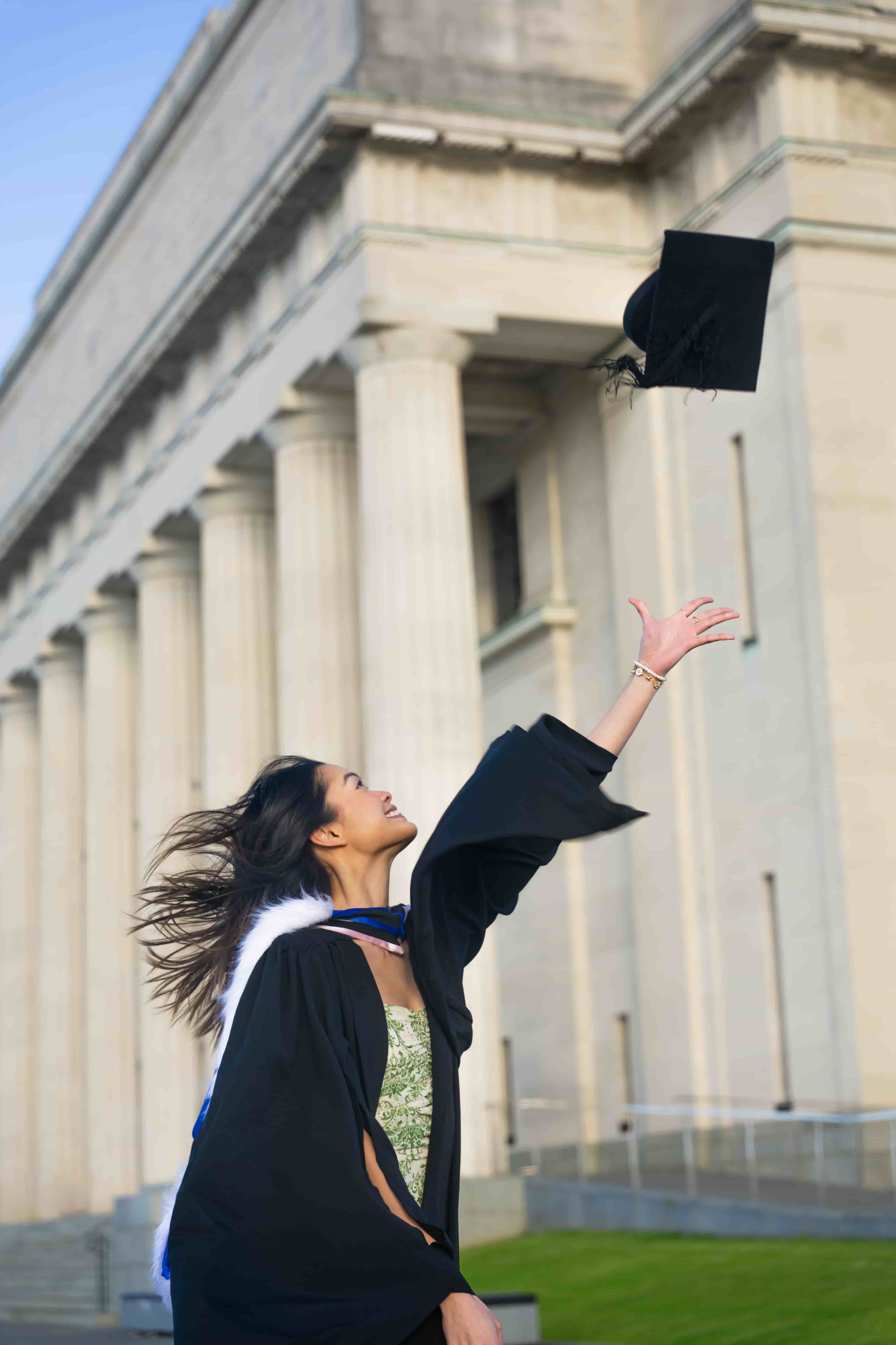 Ruby throwing her graduation cap in front of the columns of Auckland War Memorial Museum
