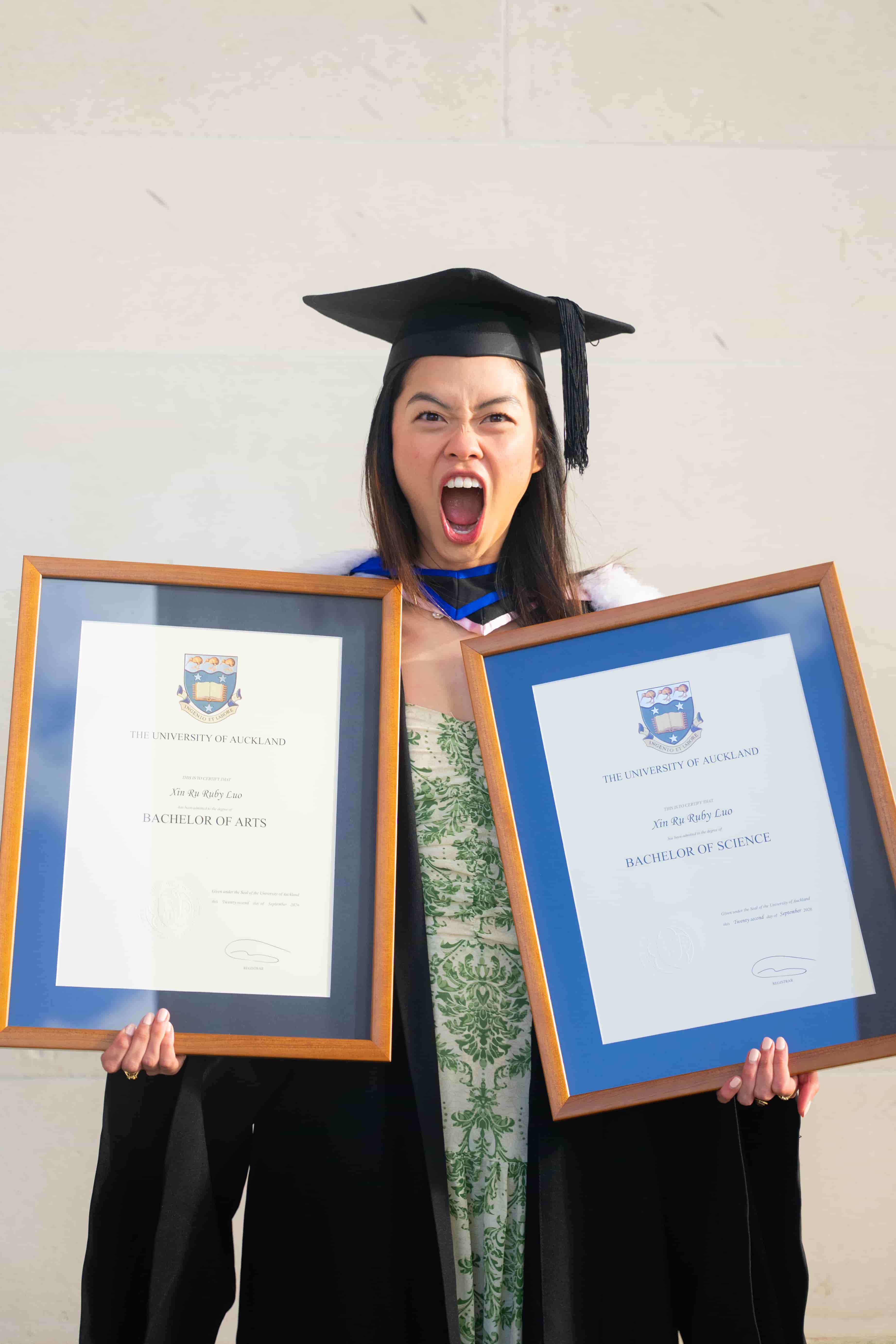 Ruby shouting with excitement while holding her University of Auckland Bachelor of Arts and Bachelor of Science degrees