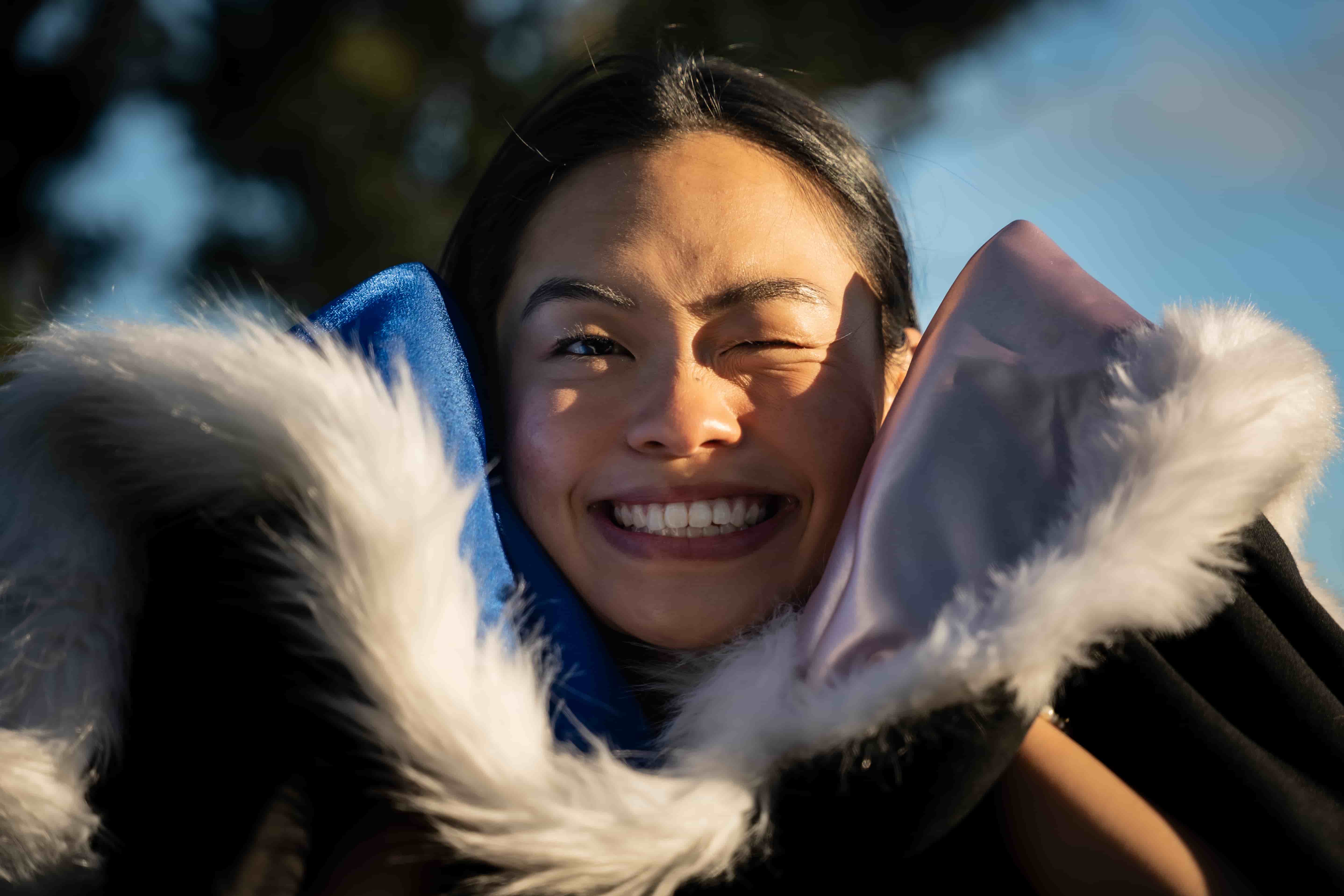 Ruby grinning with her fur-trimmed graduation hood held up to her cheeks