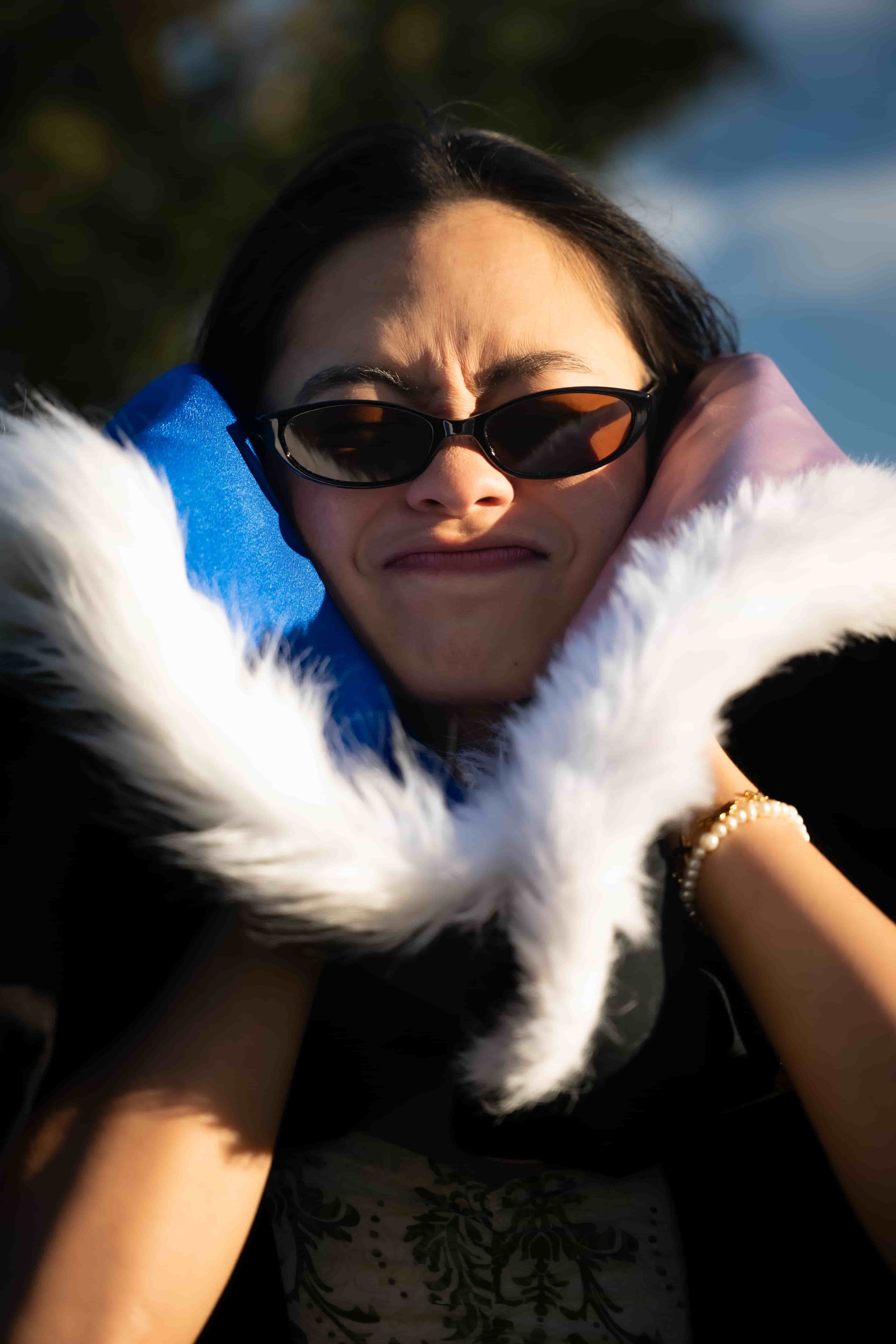 Ruby squinting in sunglasses, framed by the white fur trim of her graduation hood