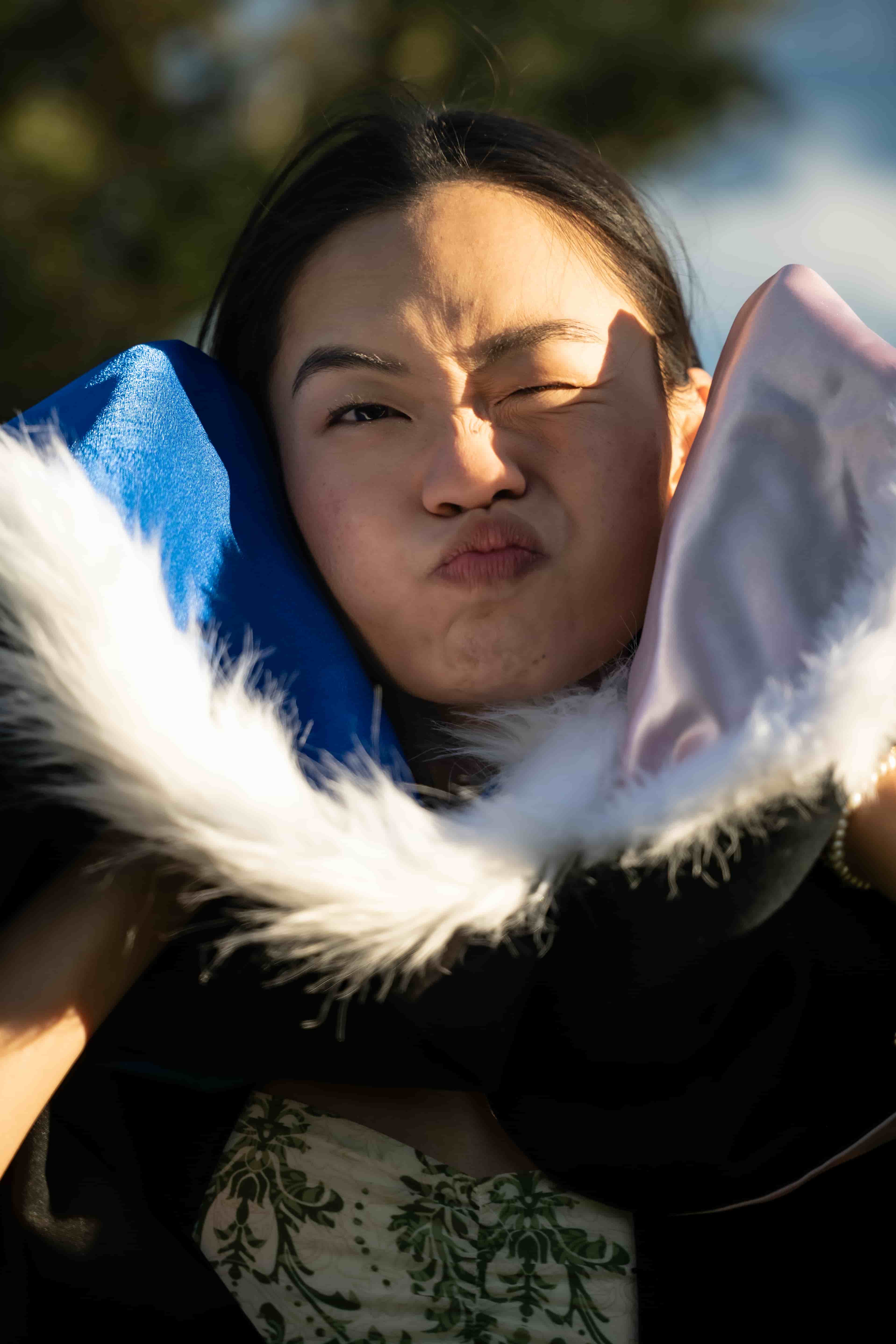 Ruby scrunching her face playfully inside her fur-trimmed graduation hood