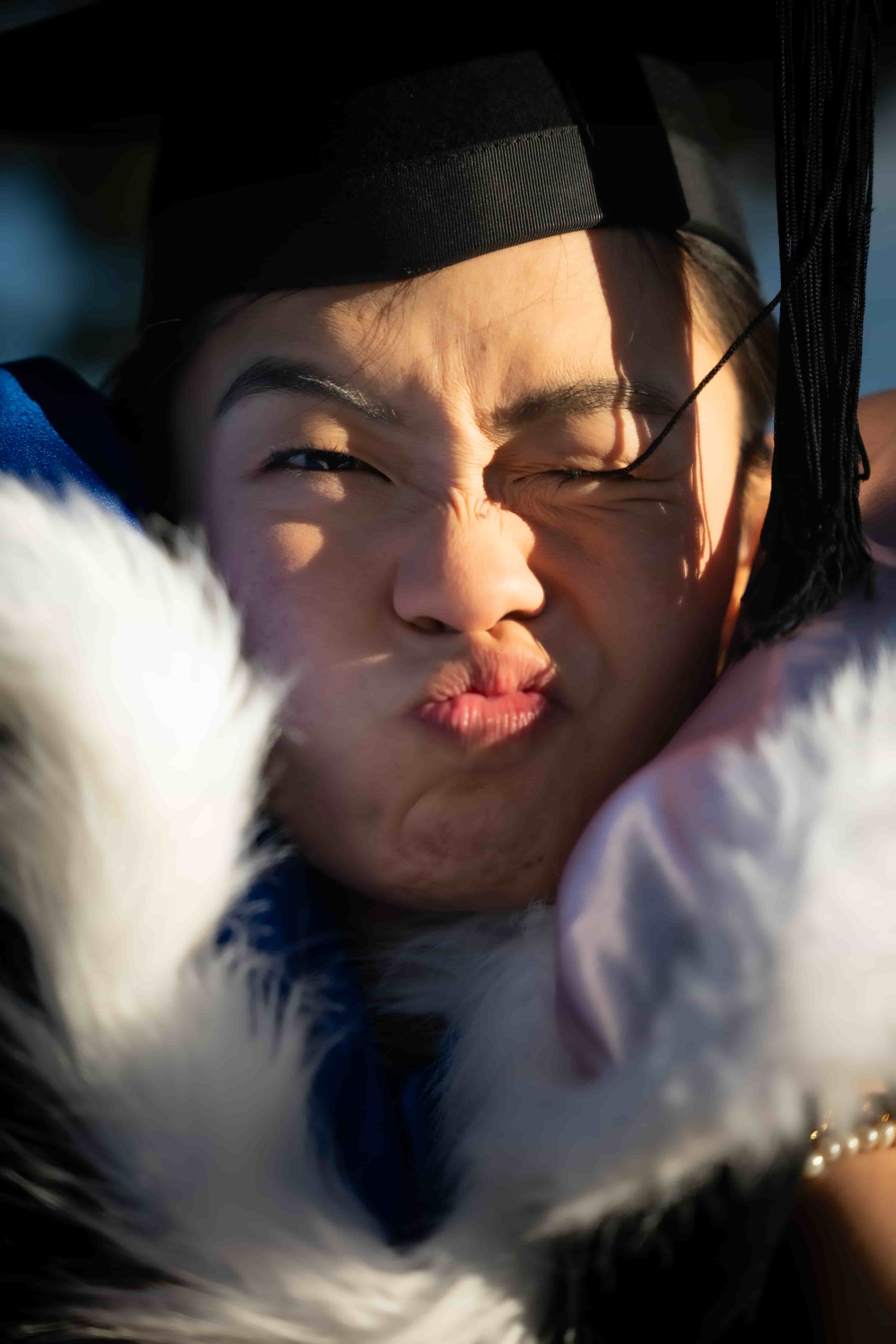 Ruby pouting in her graduation cap, framed by the white fur of her hood