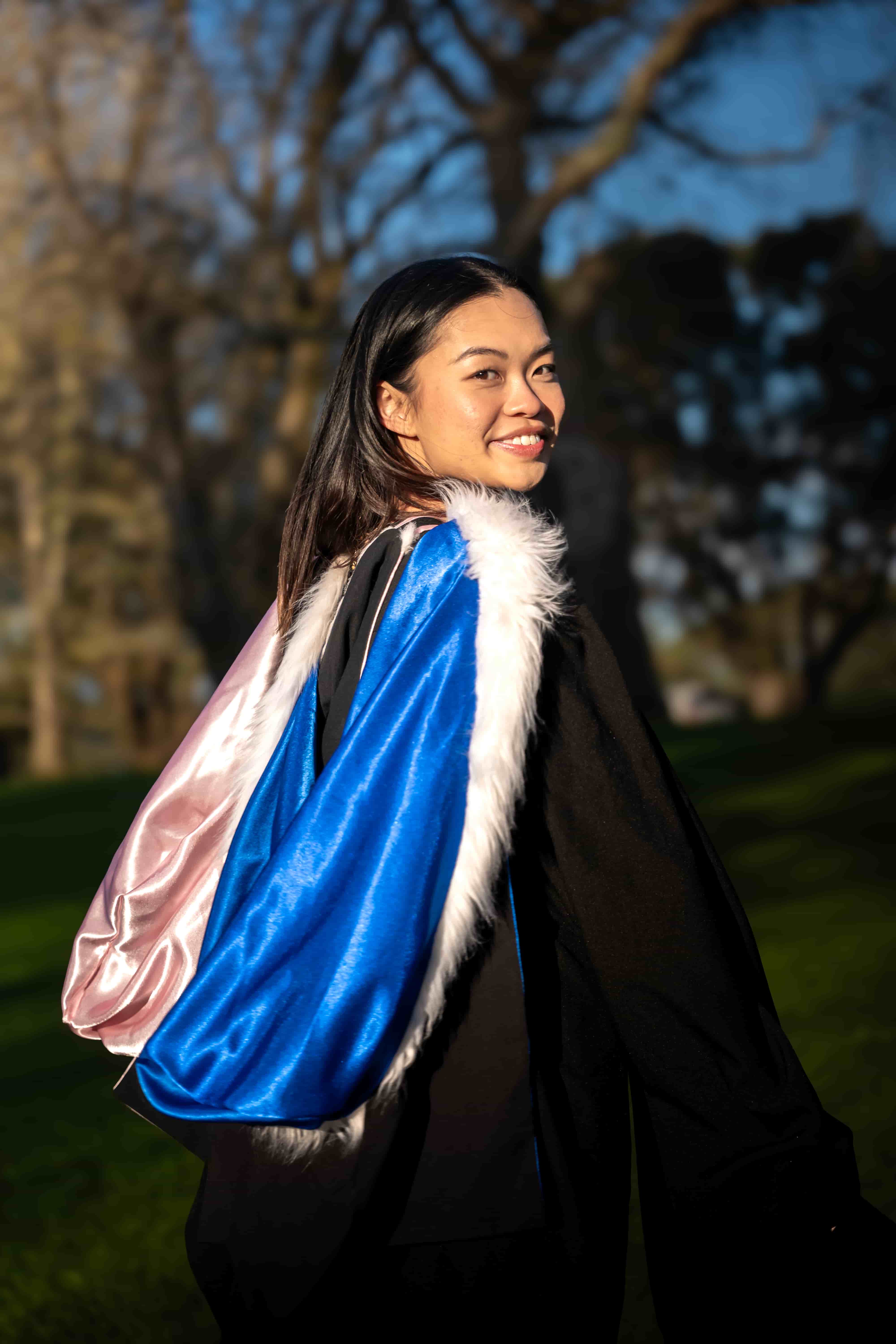 Ruby looking back over her shoulder, showing the blue and pink hood of her graduation gown