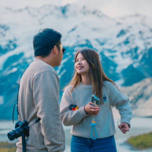 Julio and Kanis chatting and laughing in front of a snowy mountain range