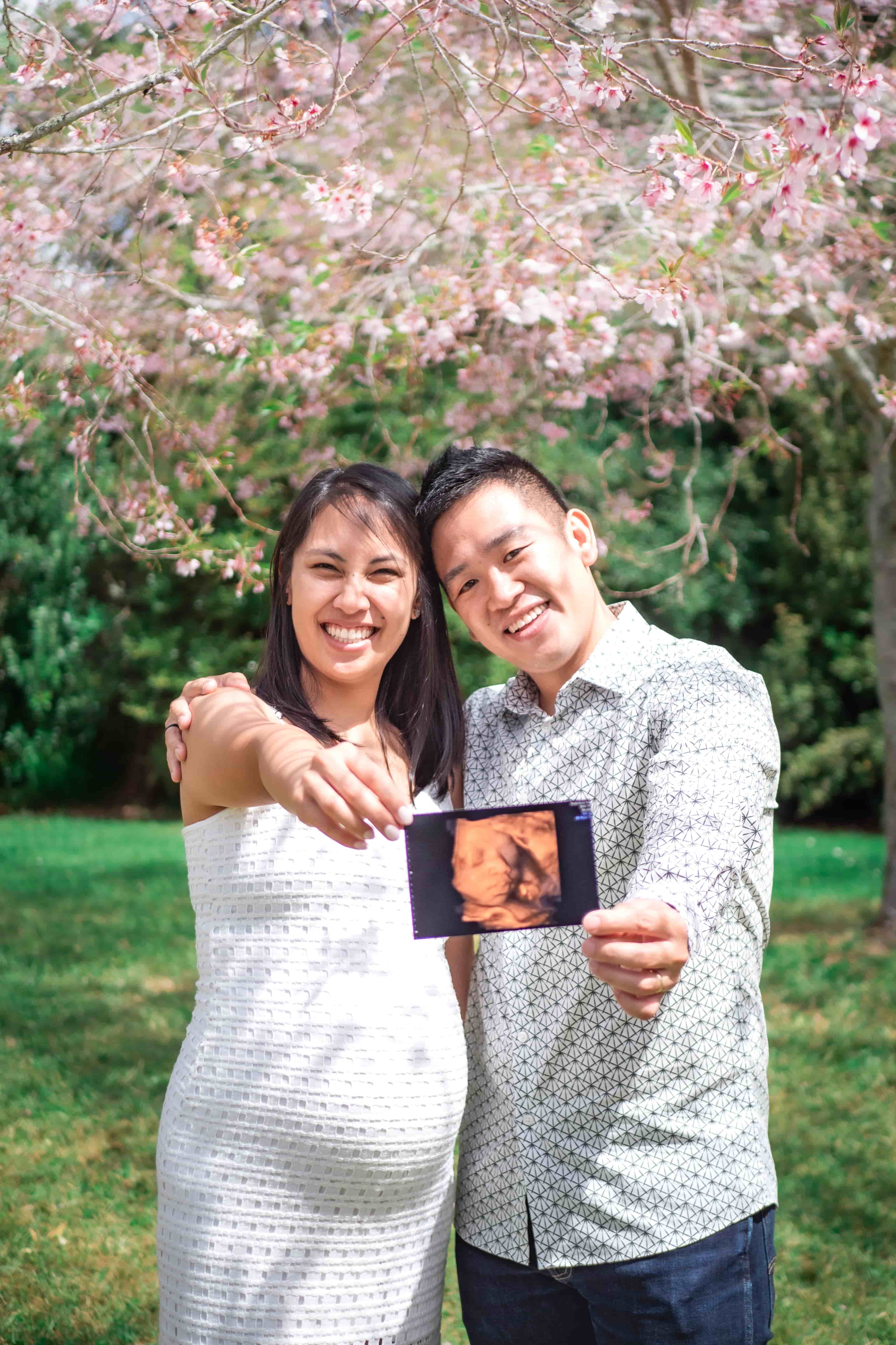 Lucas and Elisa holding the scan photo toward the camera, smiling