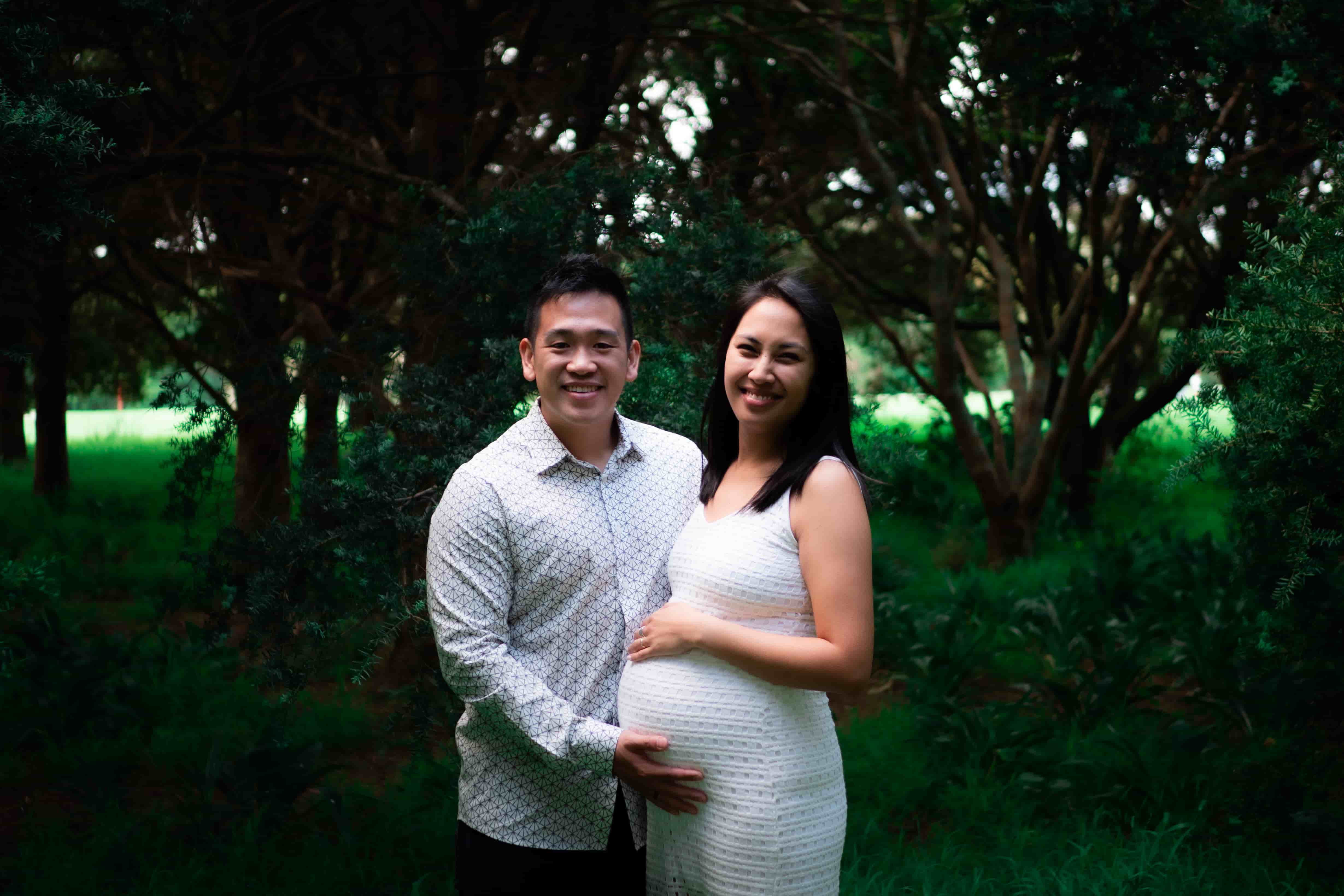 Lucas and Elisa smiling at the camera, his hand resting on her bump