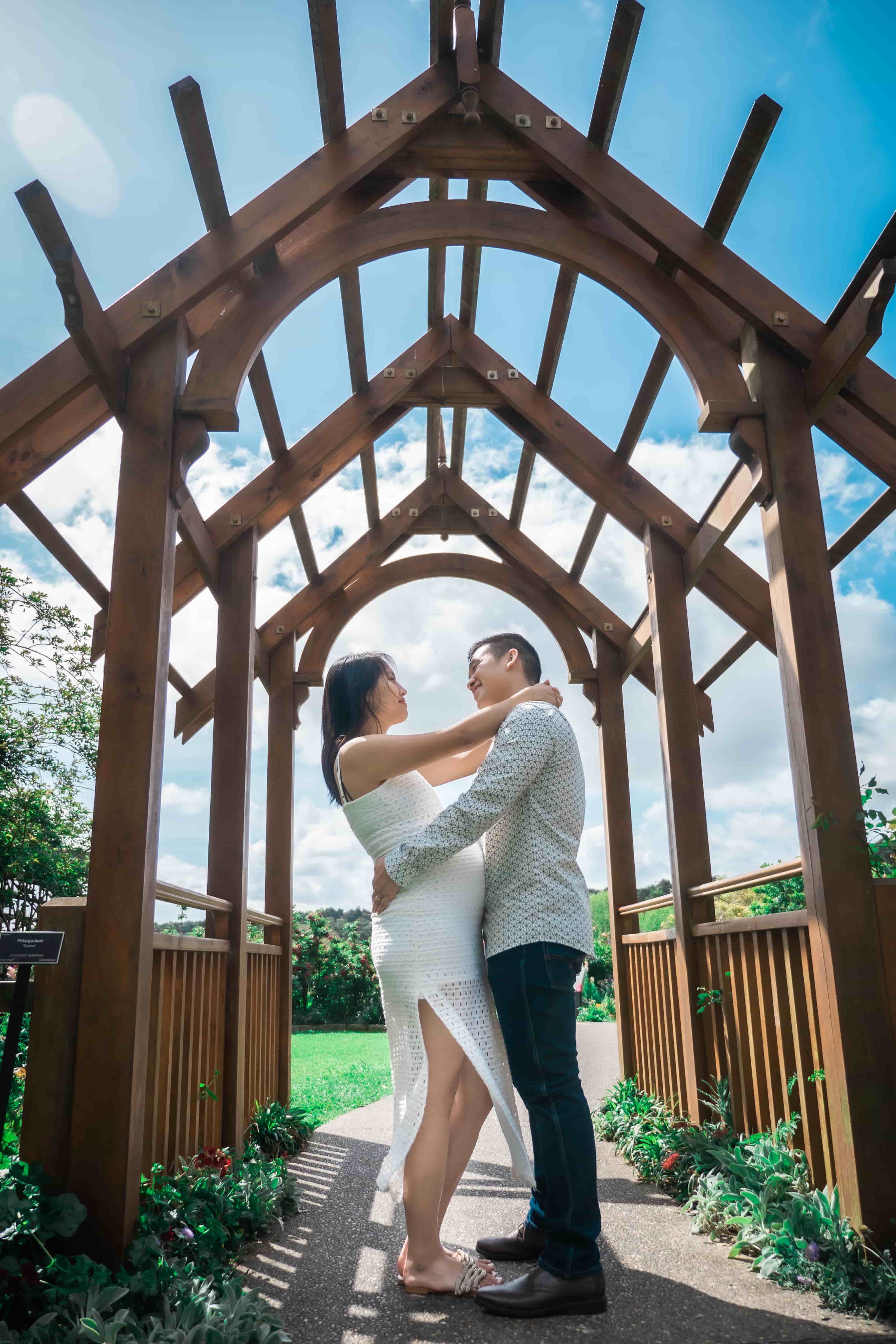 Lucas and Elisa holding each other under a wooden arch walkway