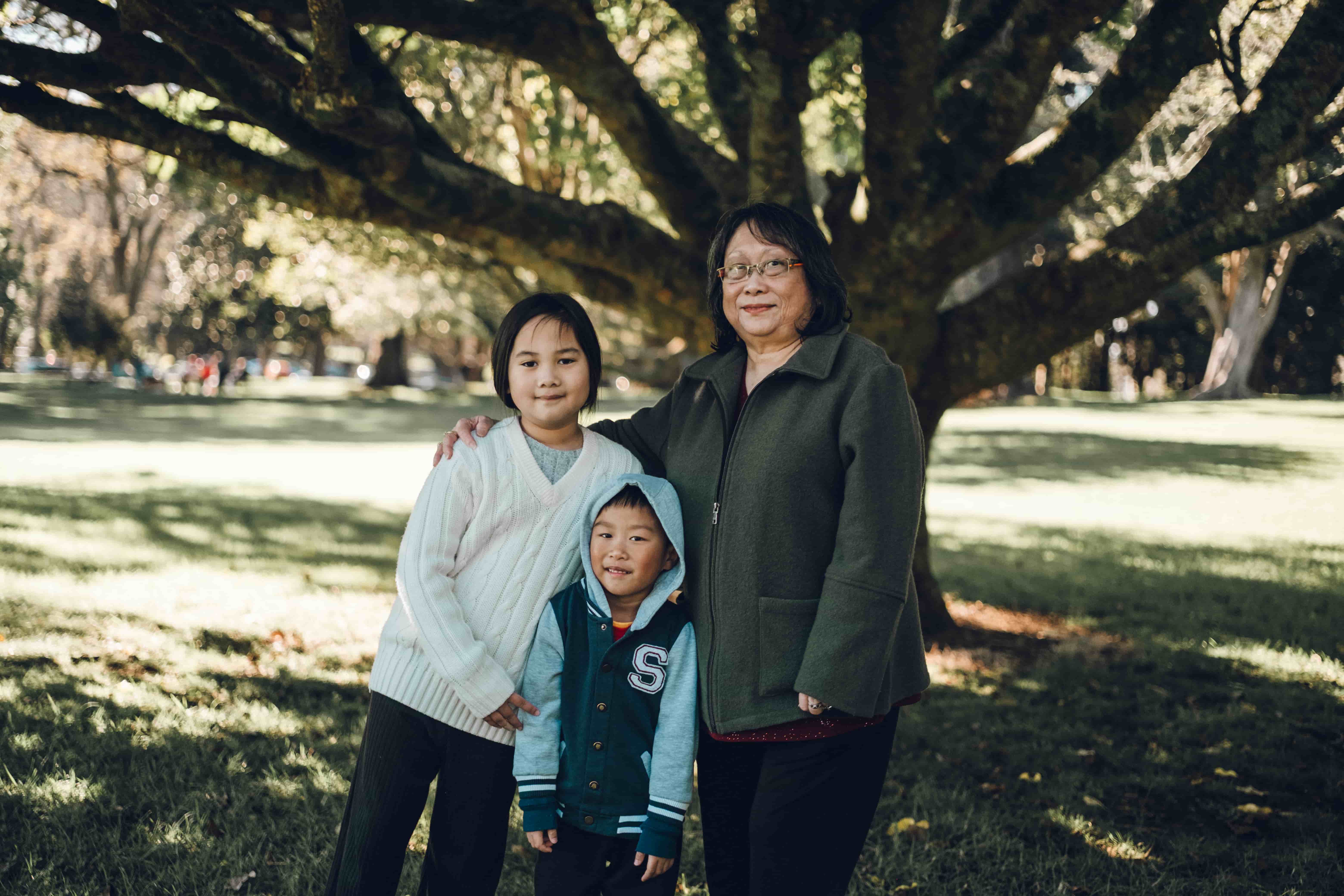 Grandmother with two grandchildren under a large tree