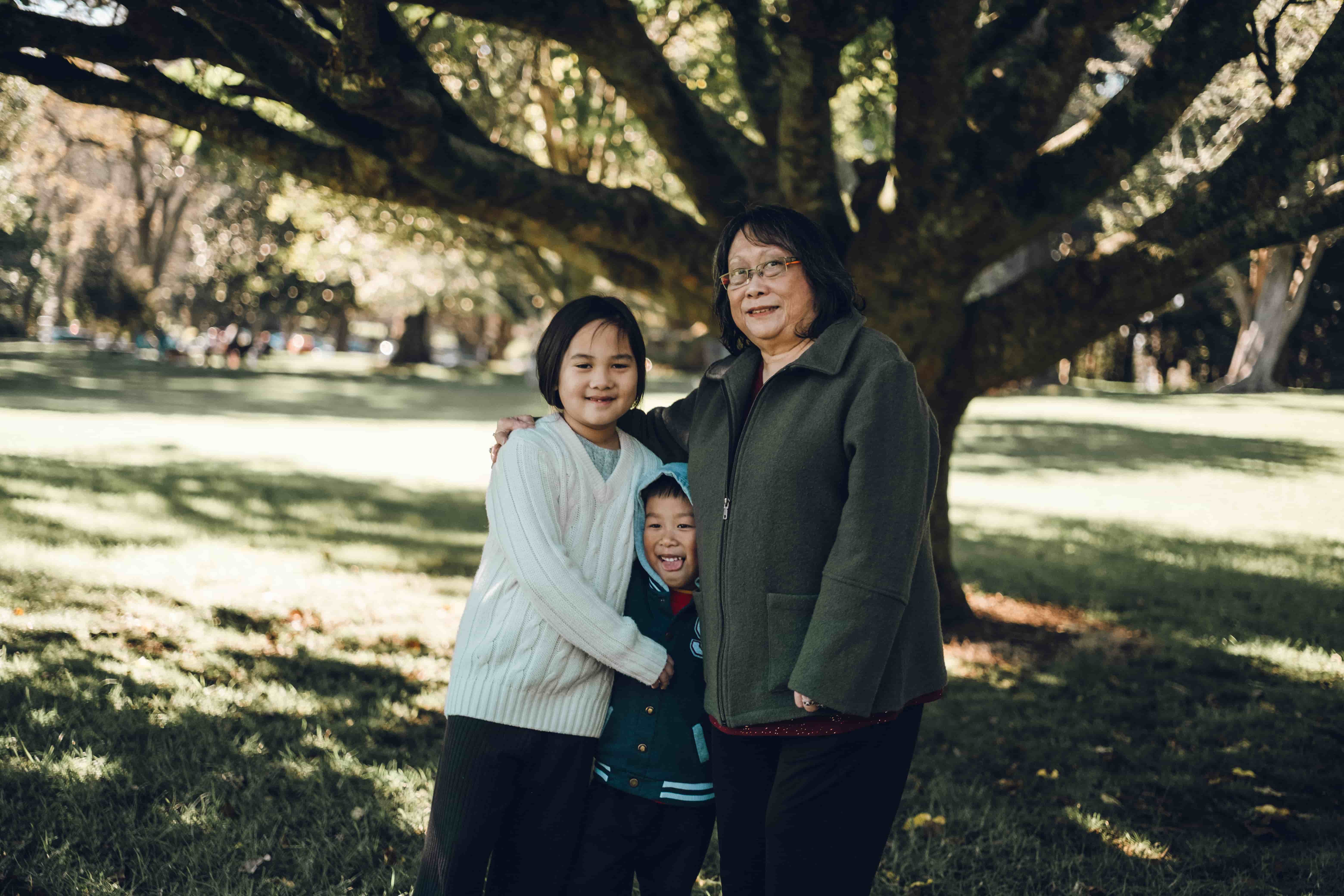 Grandmother and two grandchildren standing close on the grass