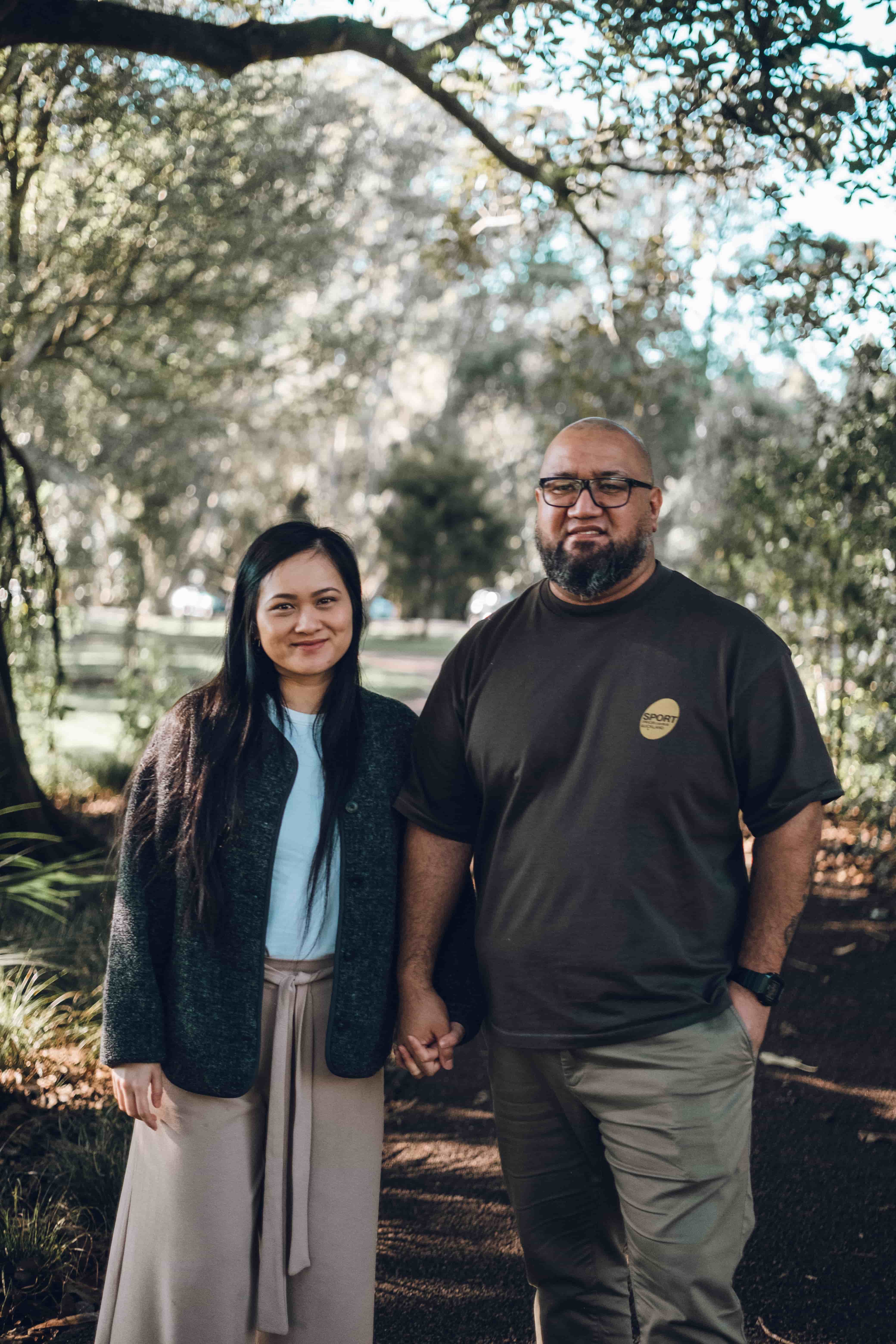 Couple holding hands on a shaded path in Cornwall Park