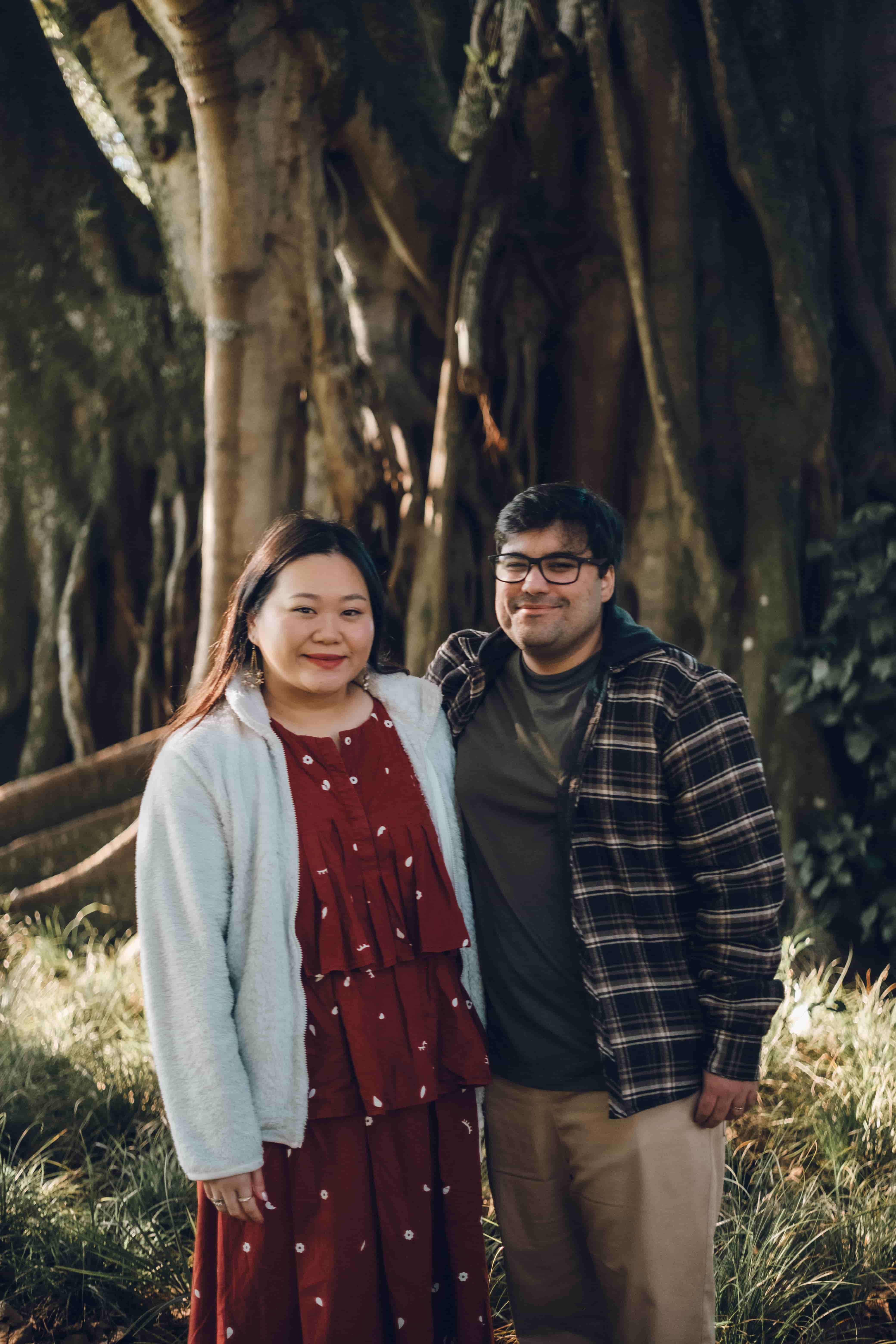 Couple standing together in front of a twisted tree trunk
