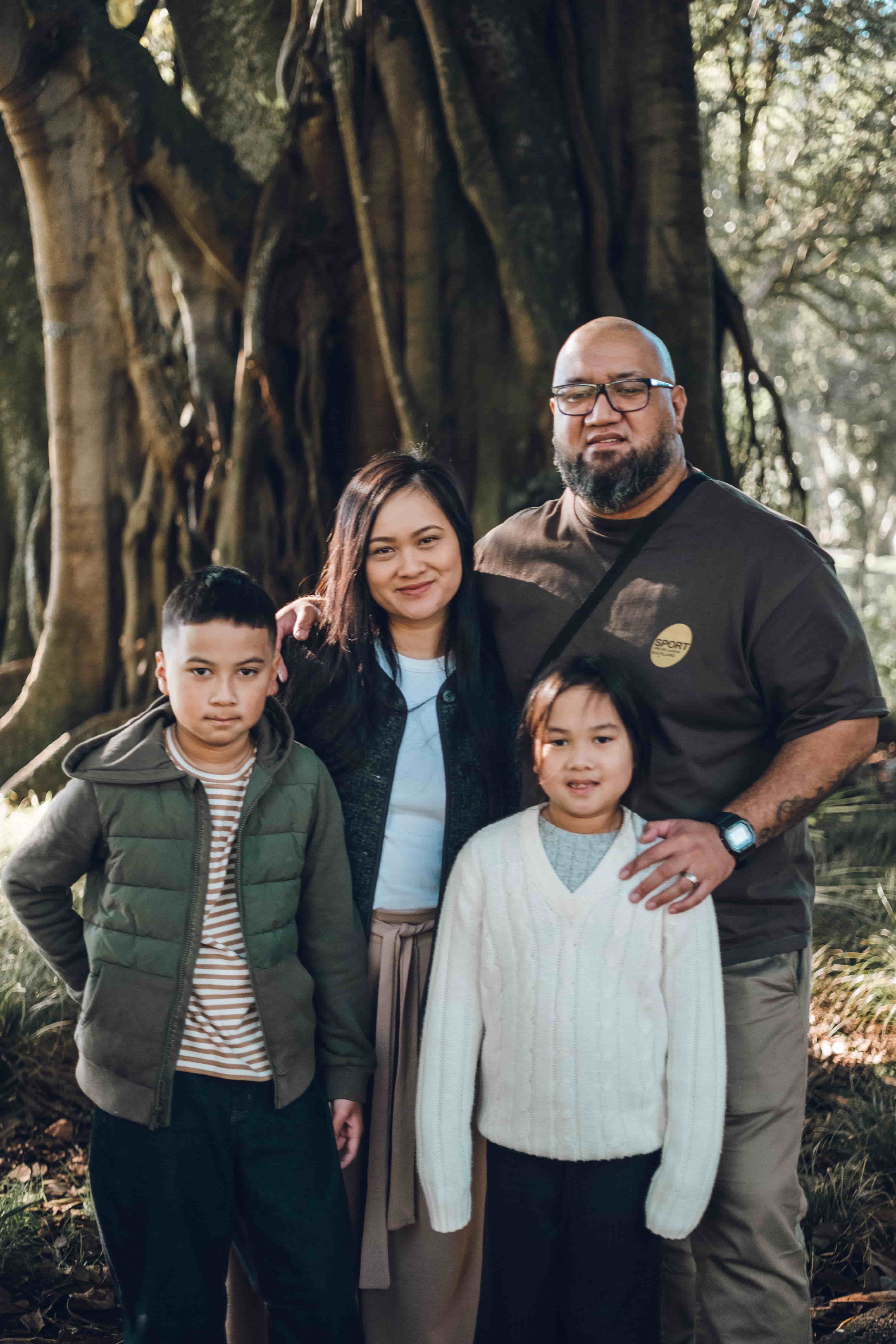 Family of four facing the camera, the father's hand on his daughter's shoulder