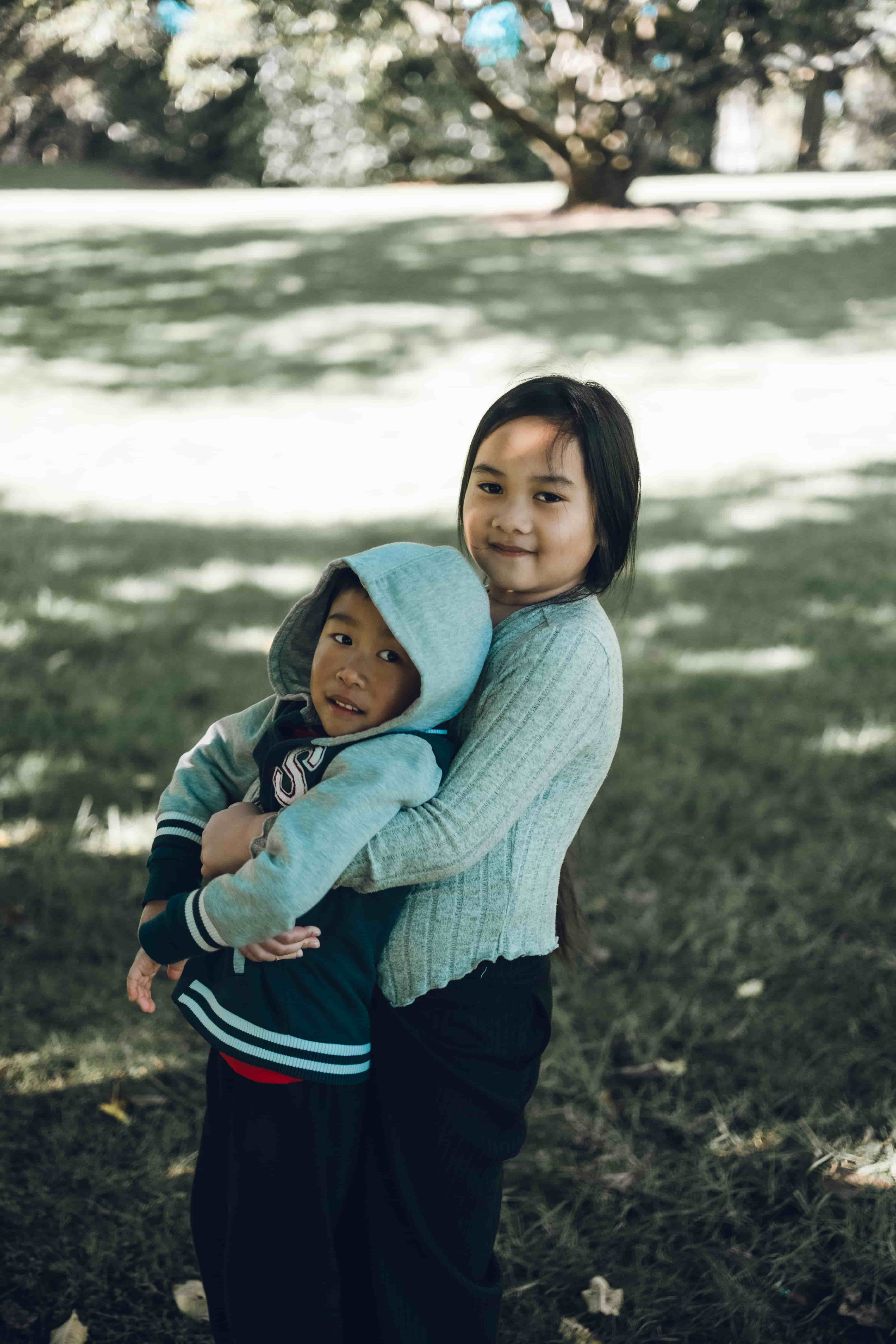 Big sister hugging her little brother on the grass