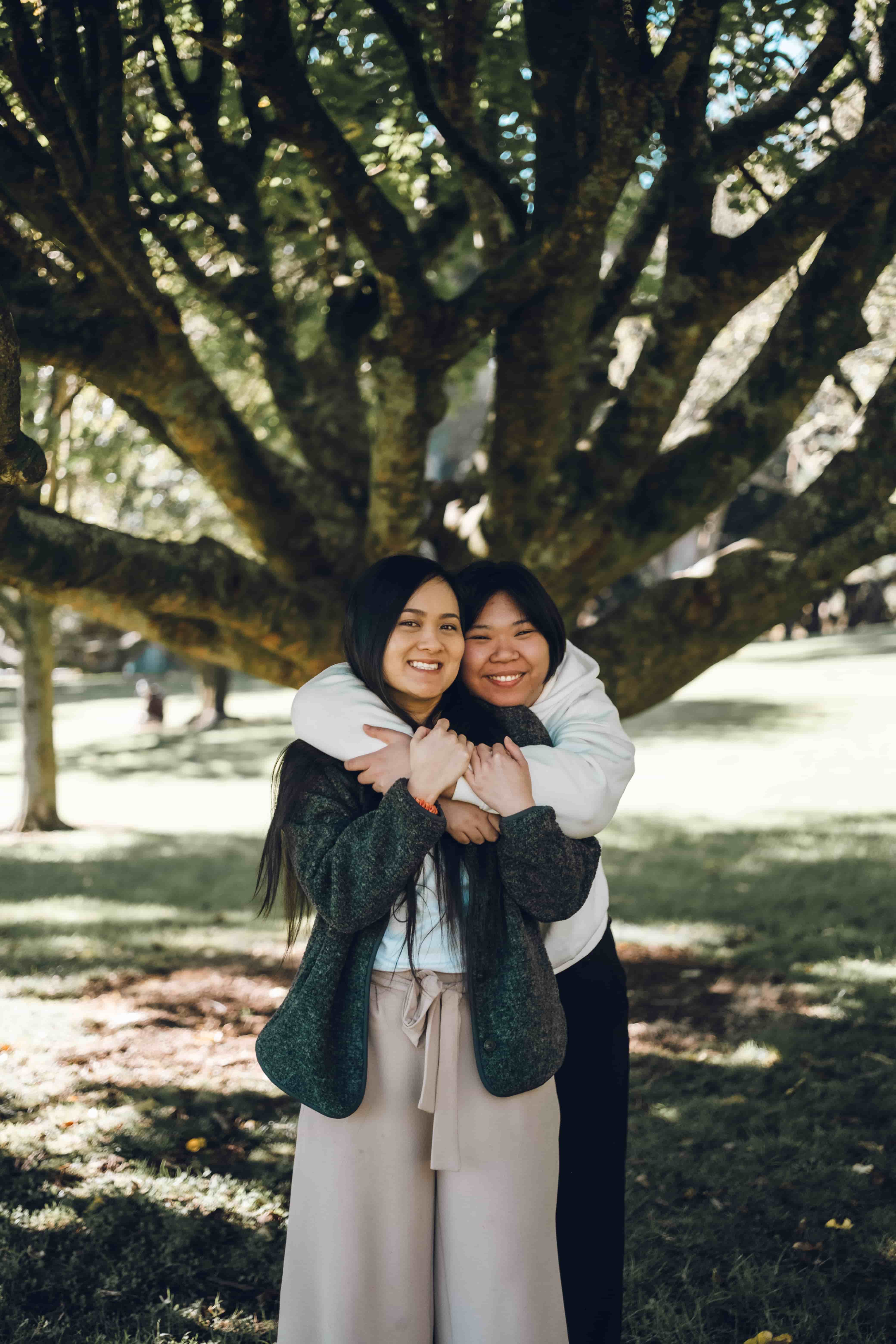 Two sisters hugging under spreading branches