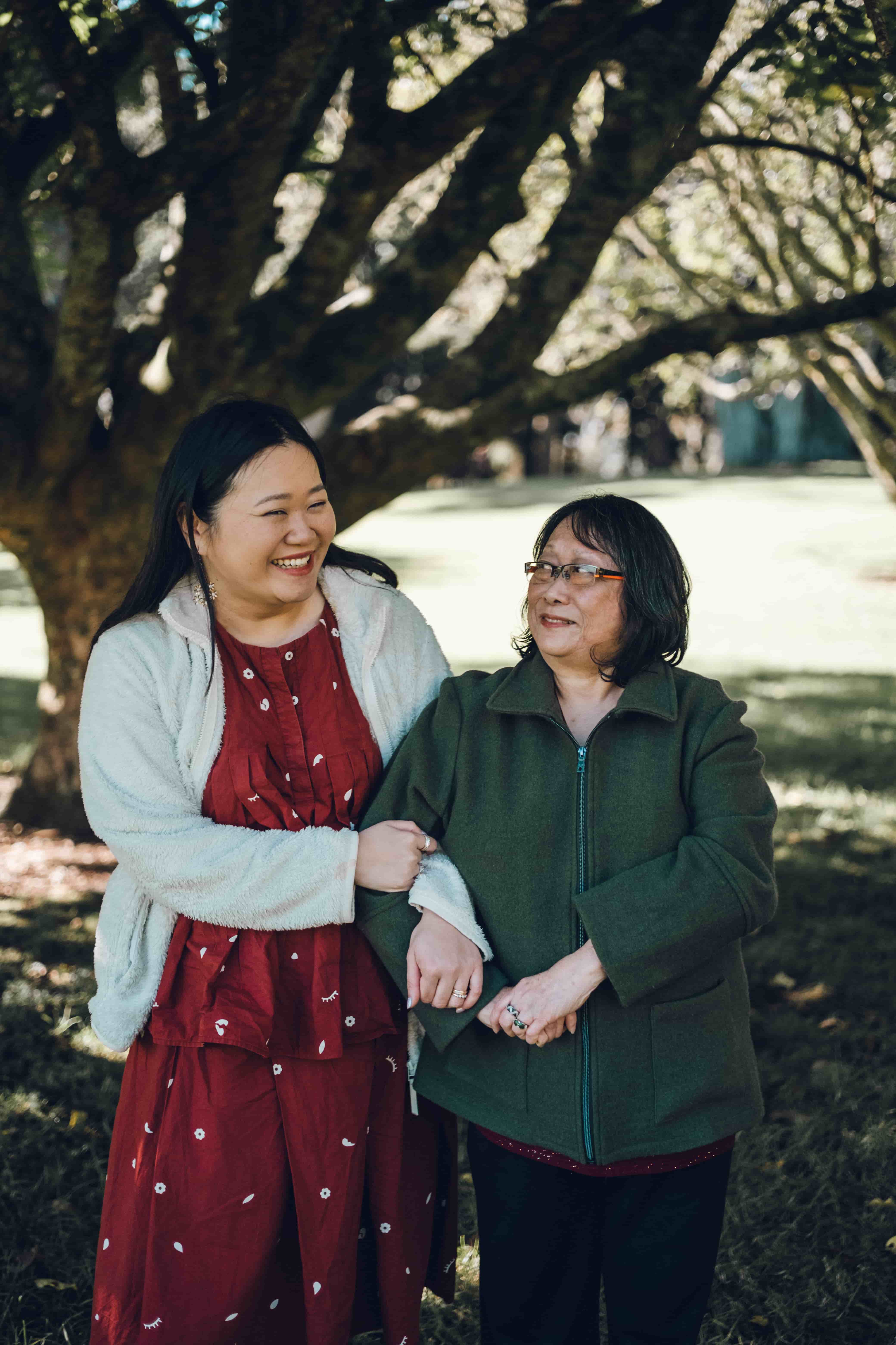 Grandmother and her daughter in a red dress, arms linked and laughing