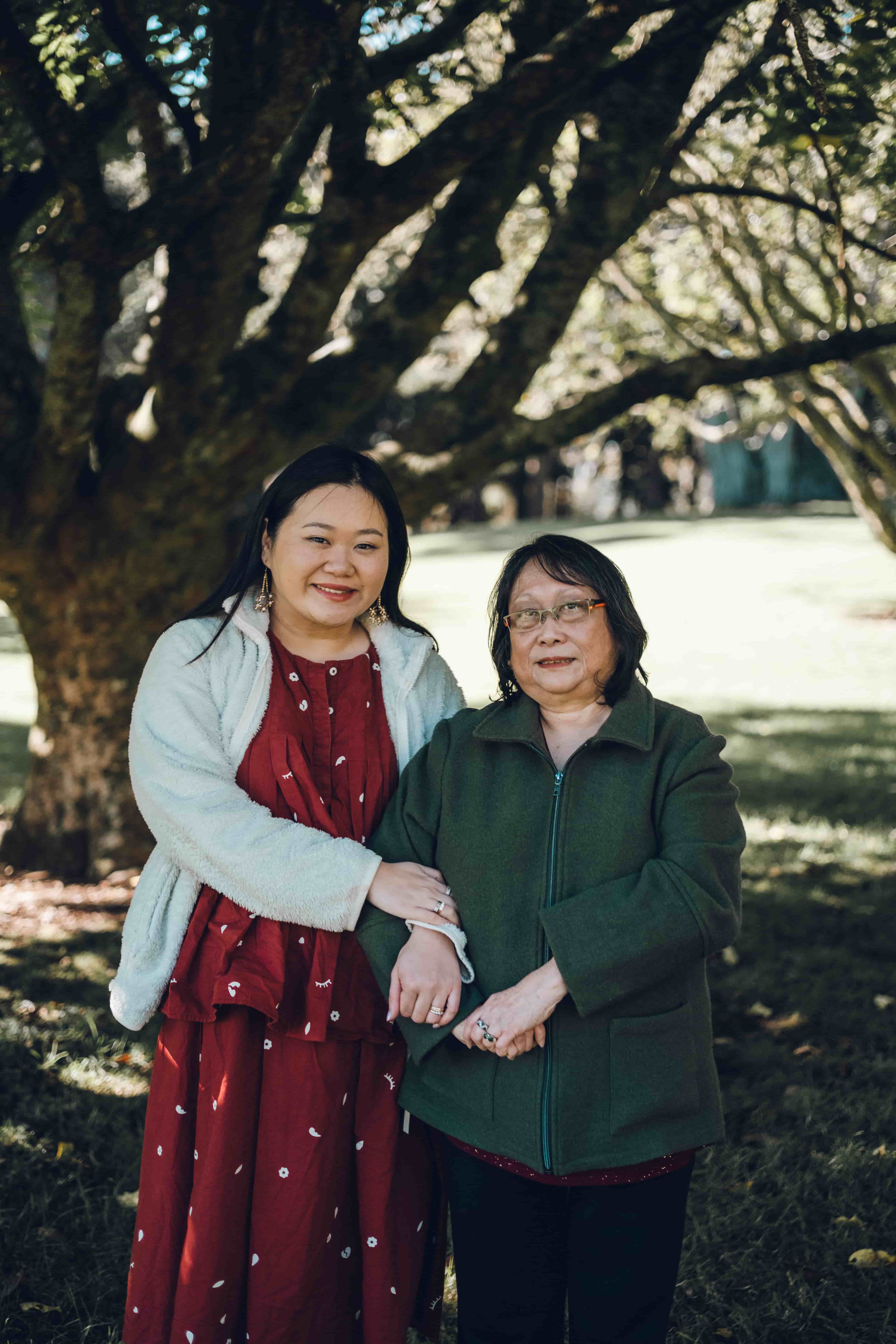 Mother and daughter smiling arm in arm on the lawn
