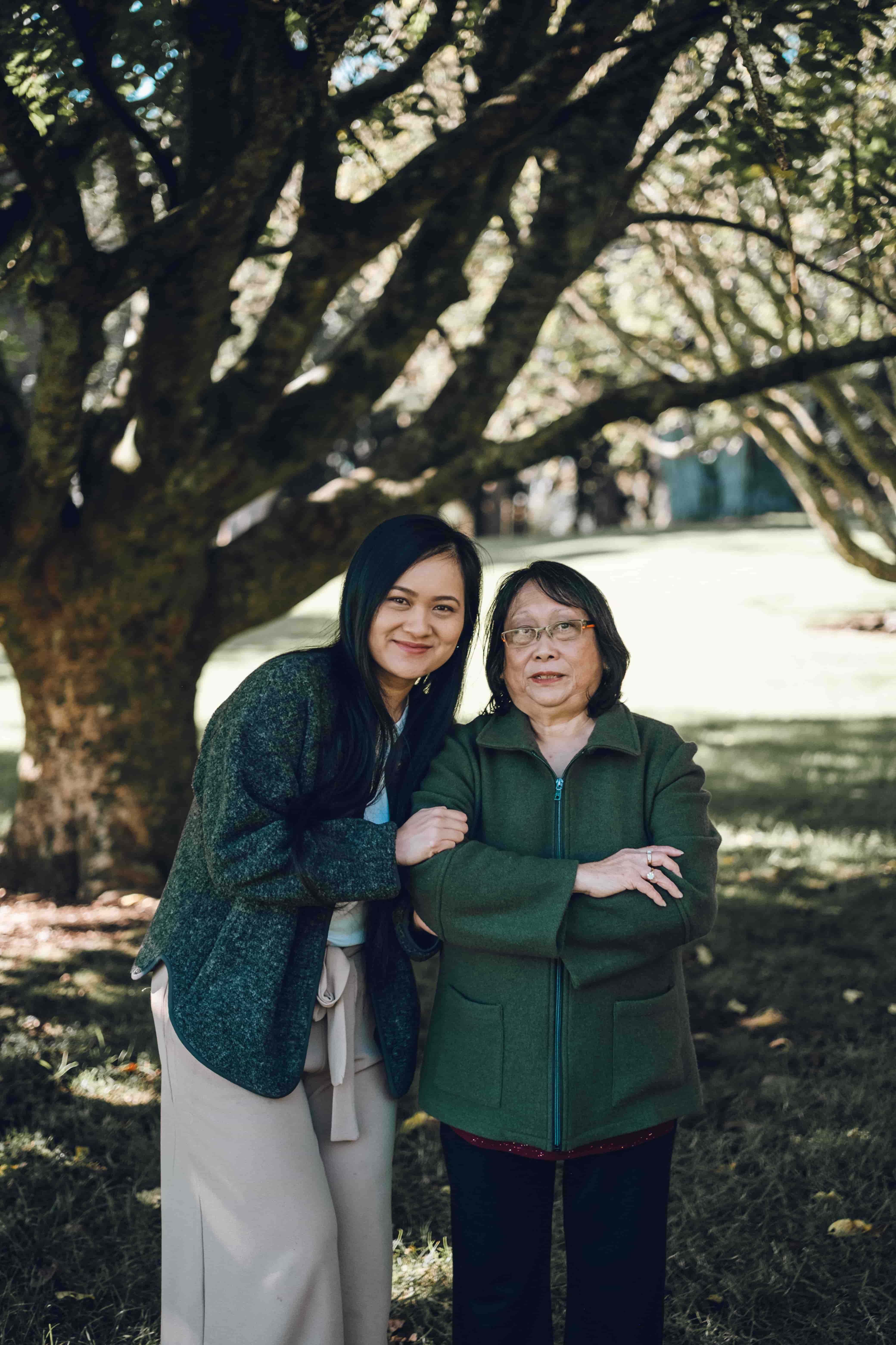 Mother and daughter arm in arm under tree branches