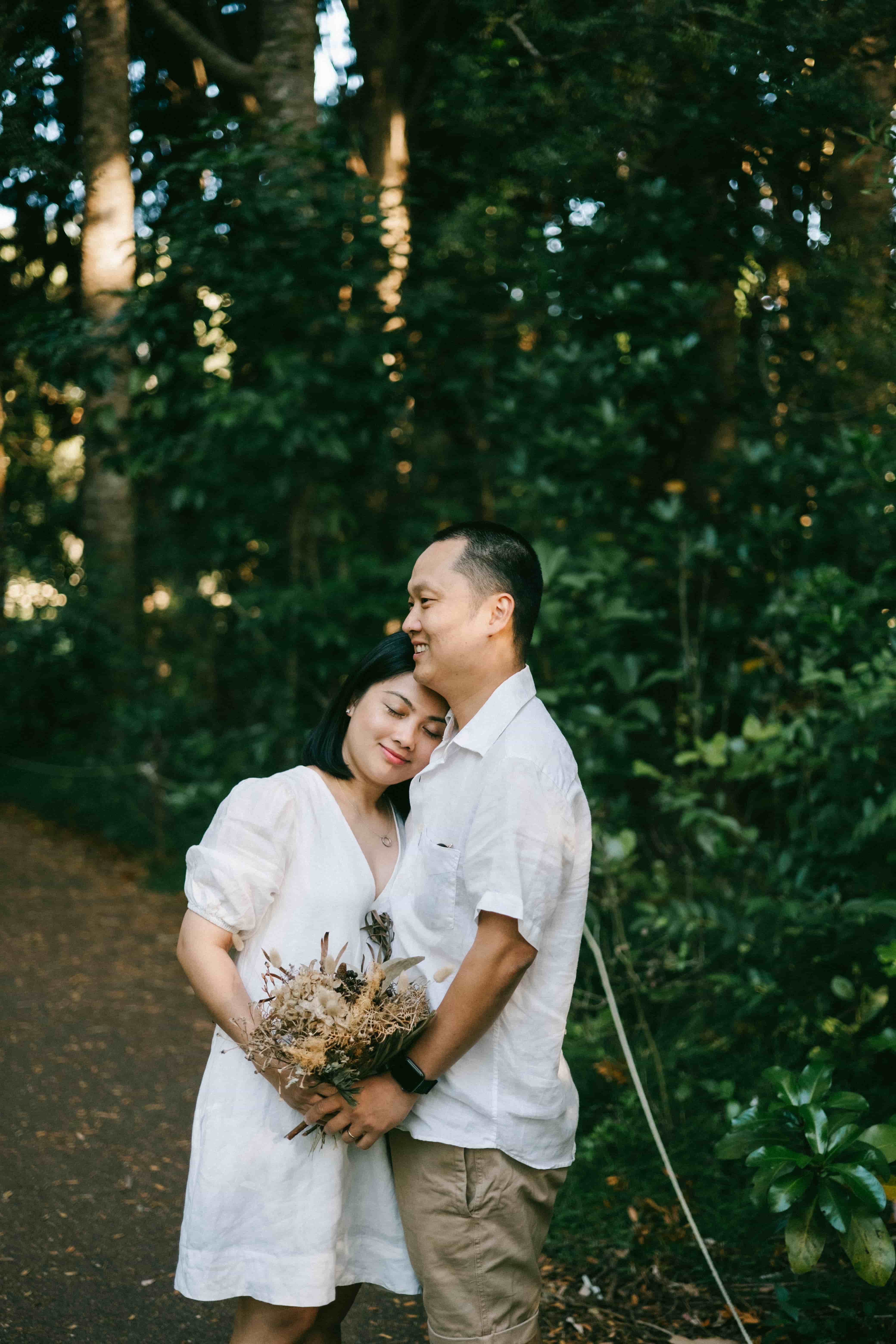 Wife resting her head on her husband's chest on a bush path