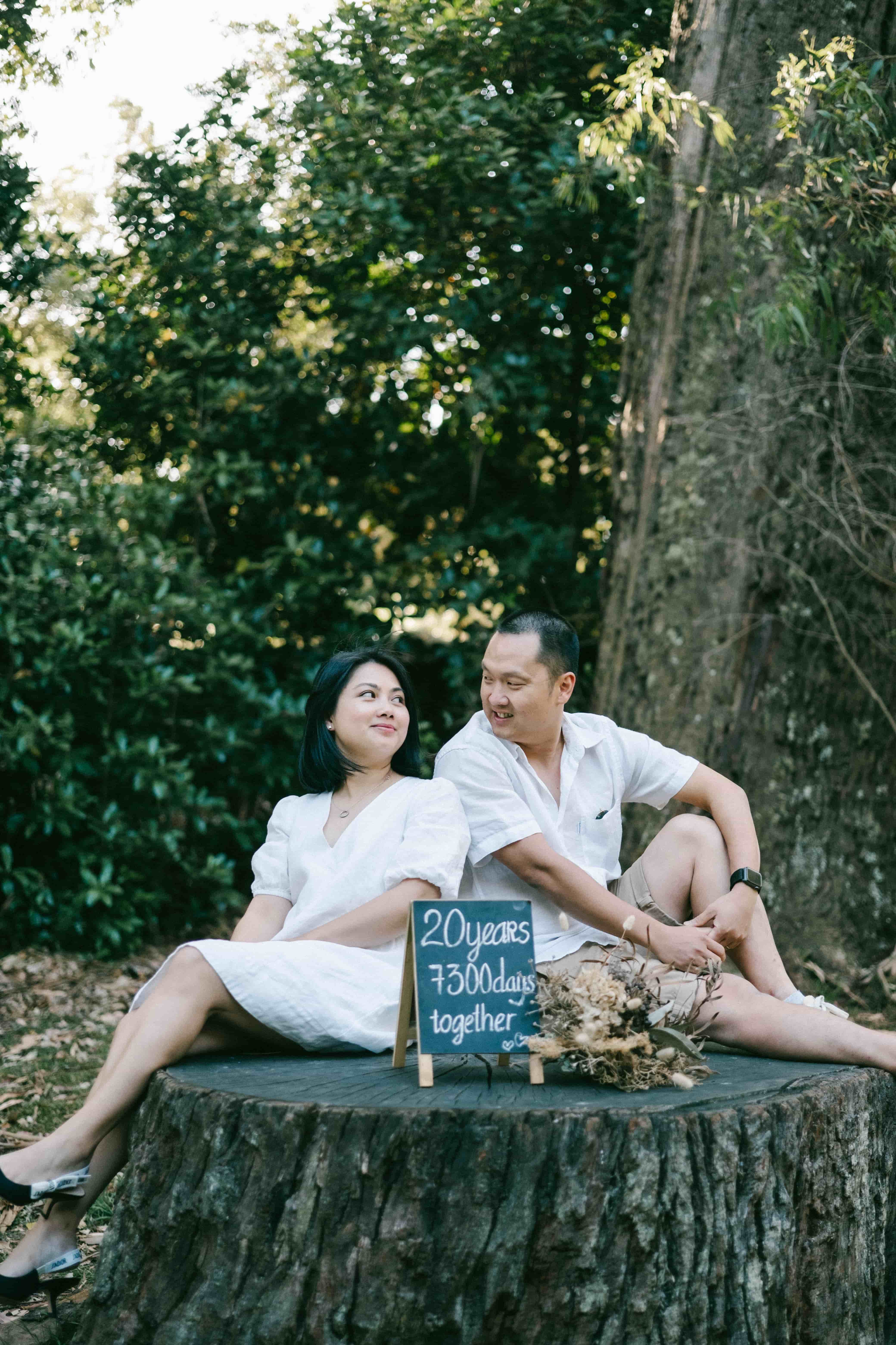 Couple sitting on a big tree stump, laughing
