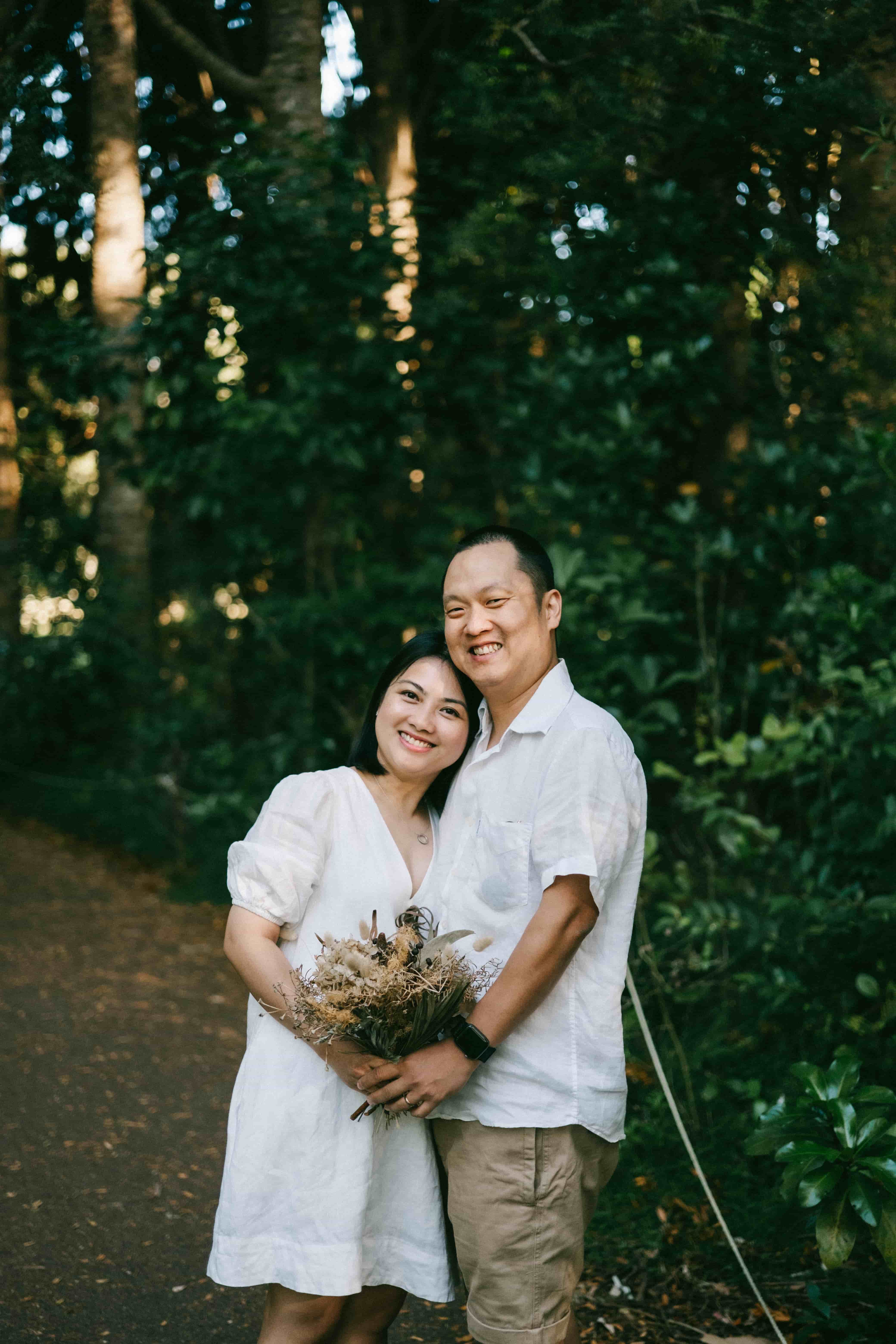 Couple smiling at the camera among tall trees