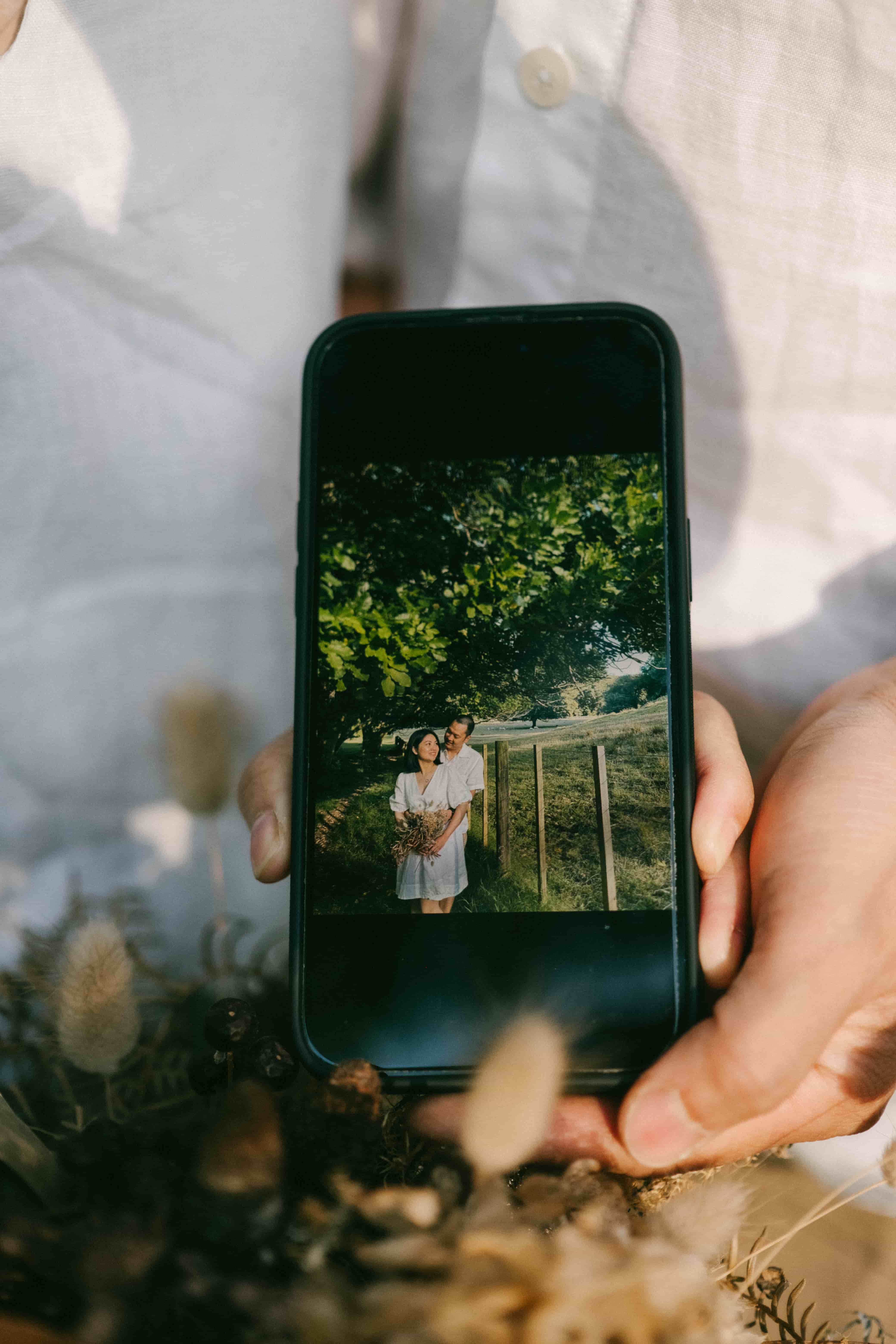 Hands holding a phone that shows a photo of the couple