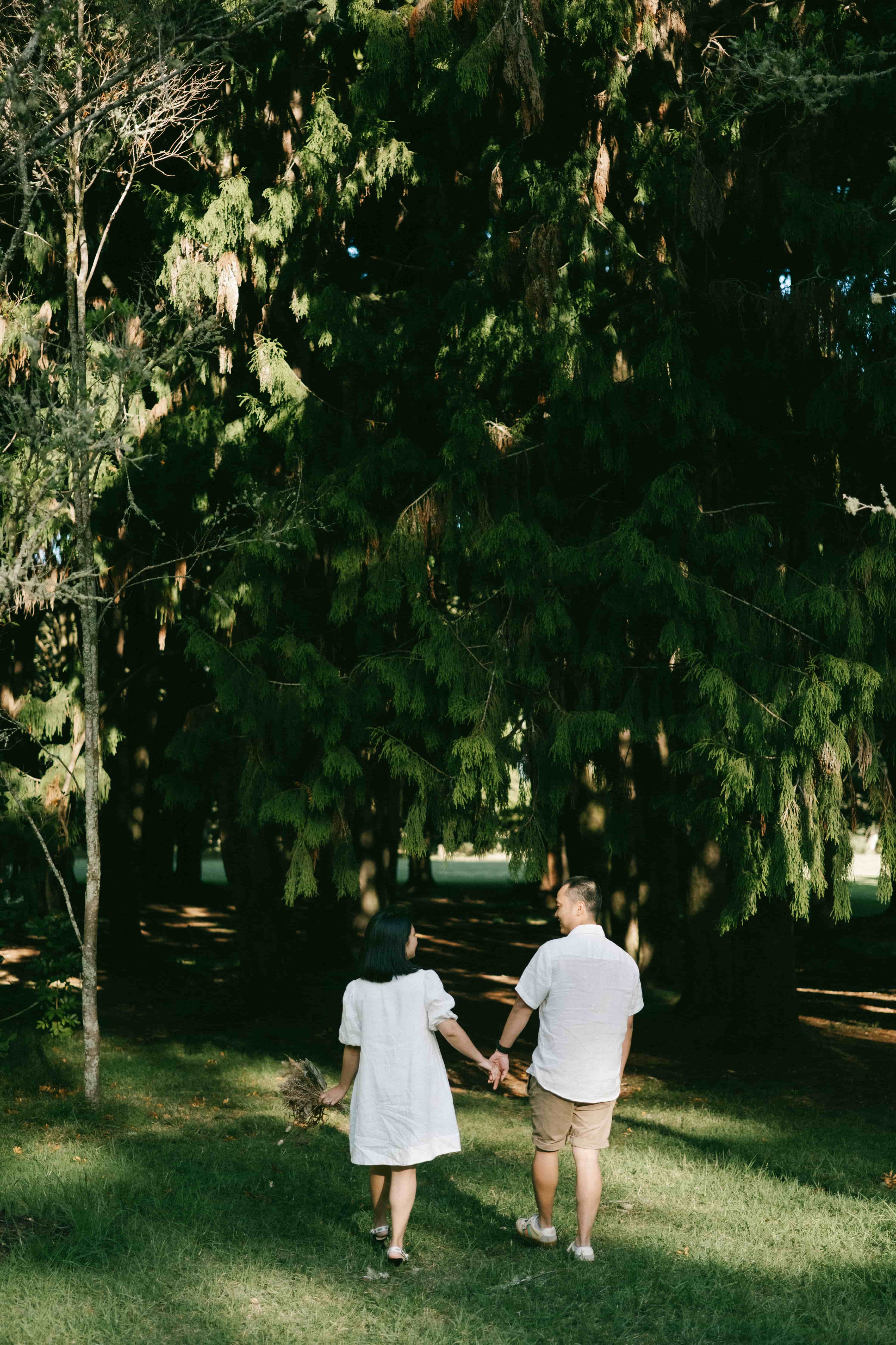 Couple walking hand in hand toward the trees