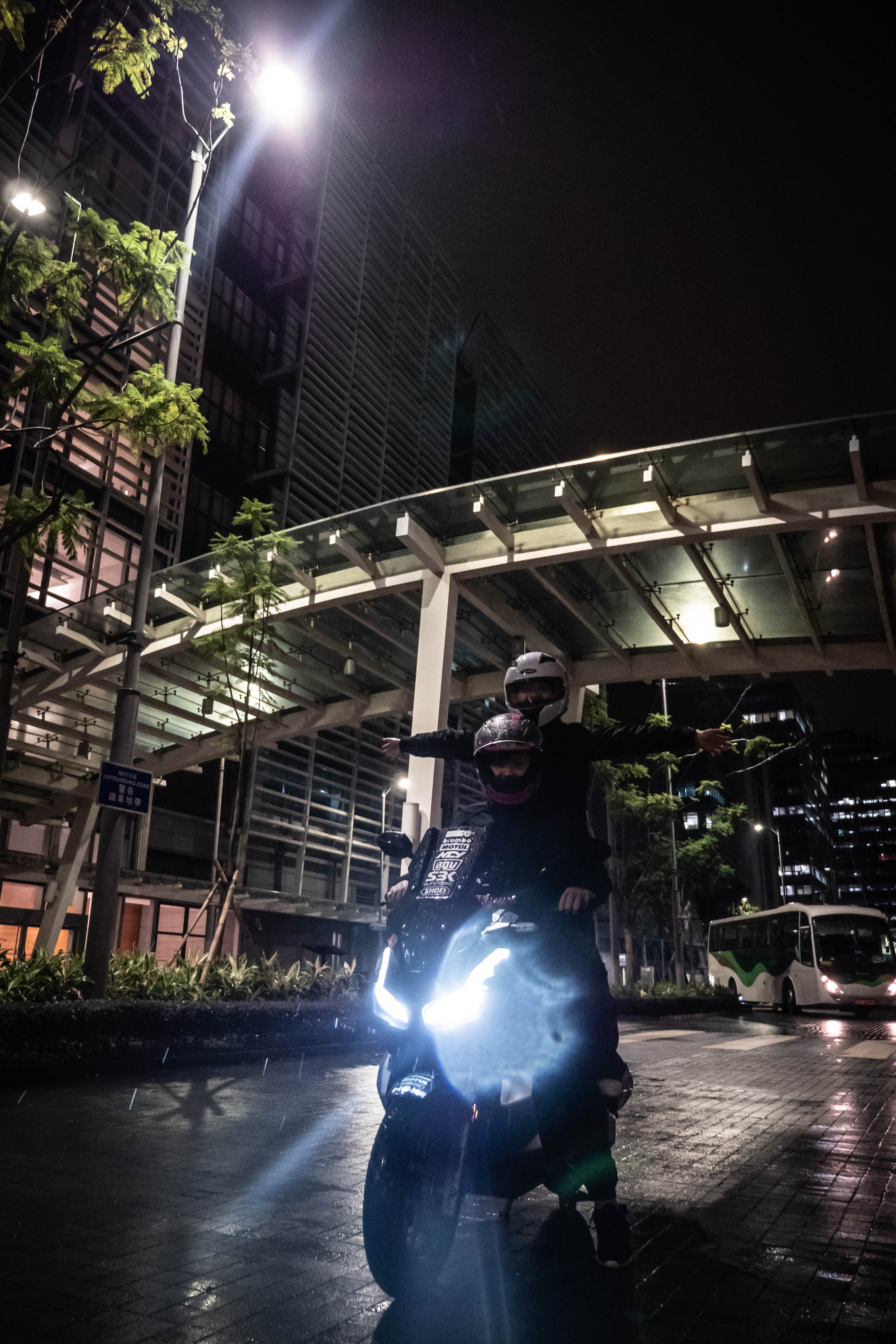 Motorcycle headlight flaring toward the camera under city lights