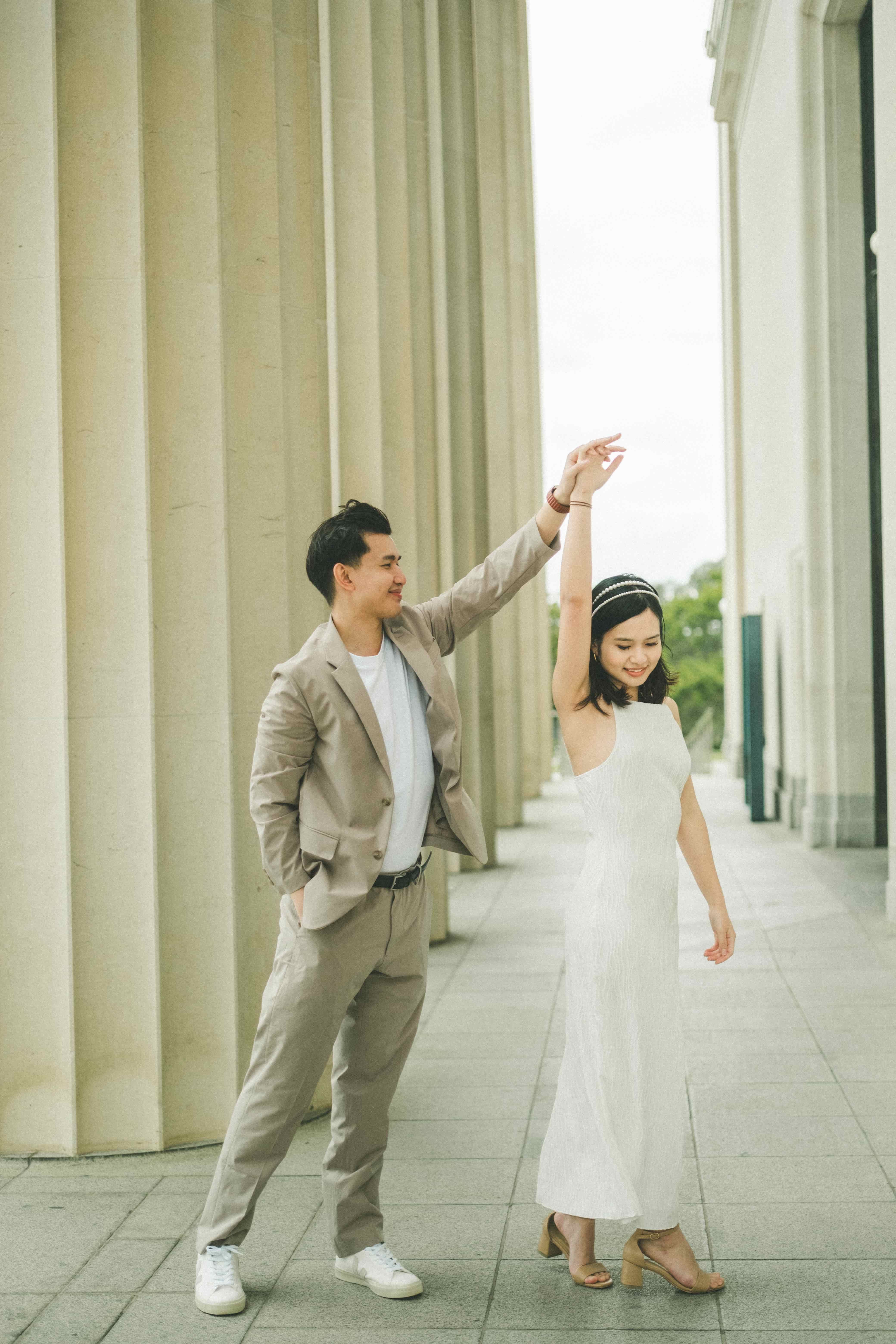 Nick twirling Suzen in her white slip dress along a colonnade of tall stone pillars