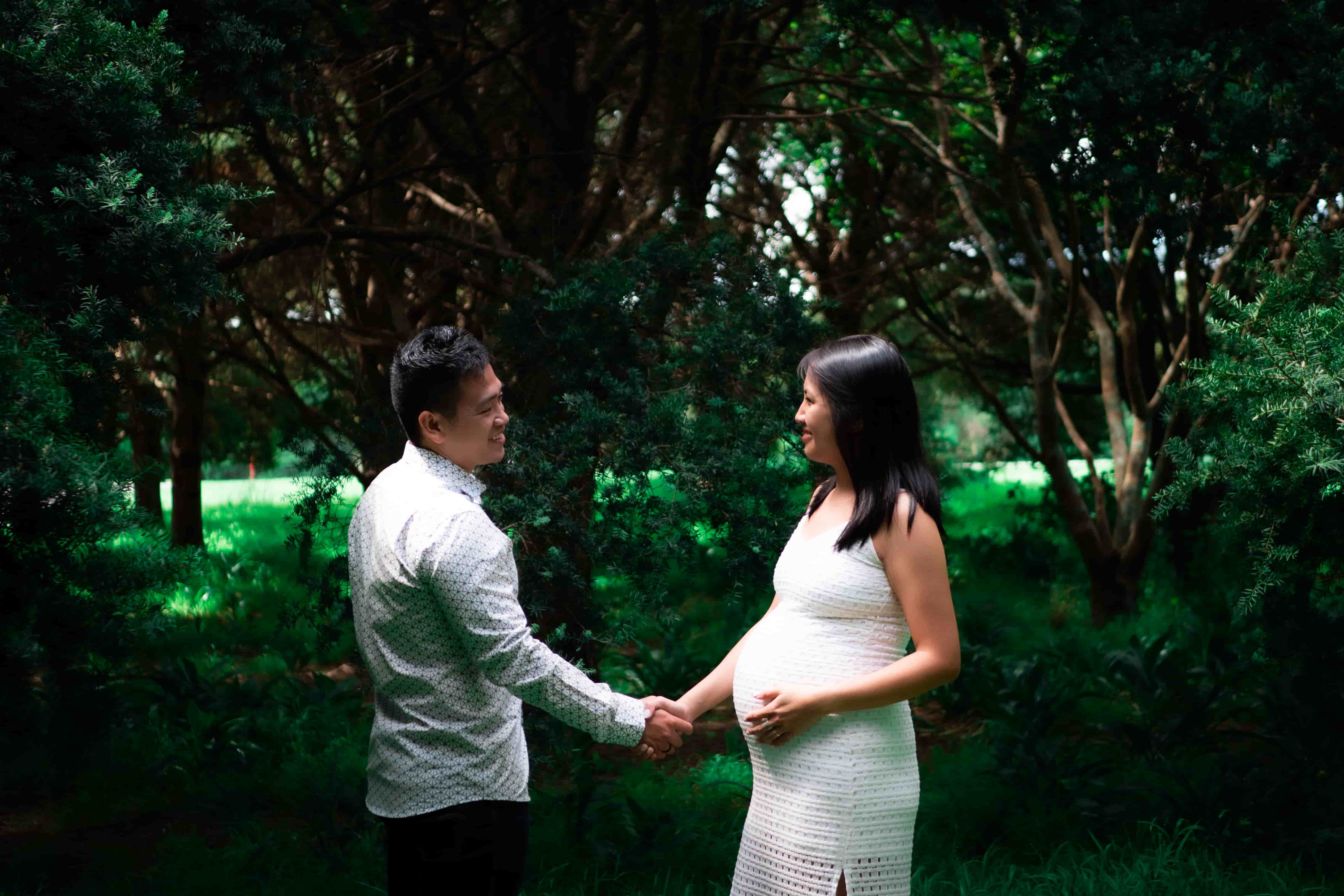 Lucas and Elisa holding hands across a shaded lawn edged with trees
