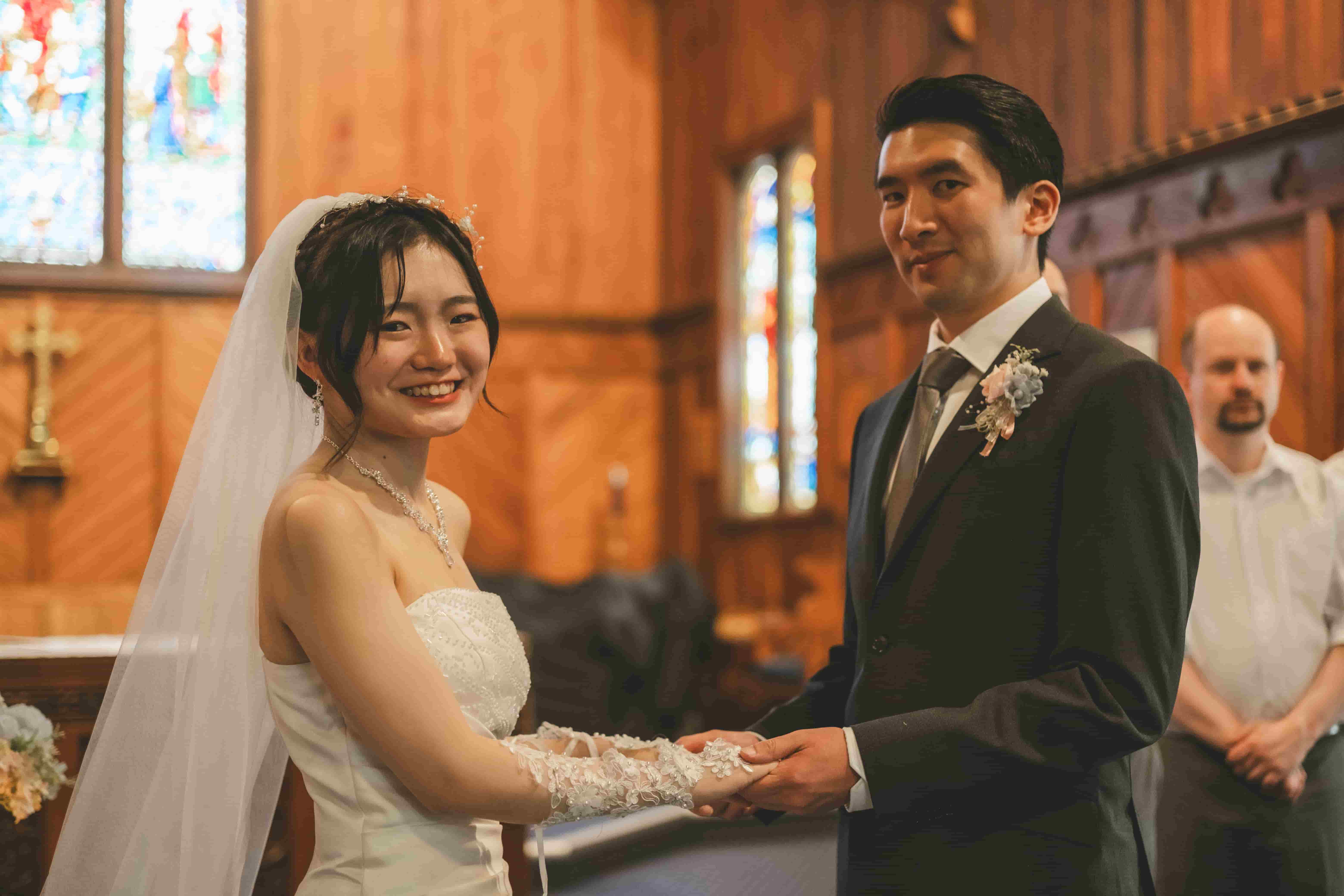 Chrystynn smiling as Hans holds her hands during their vows in a timber church