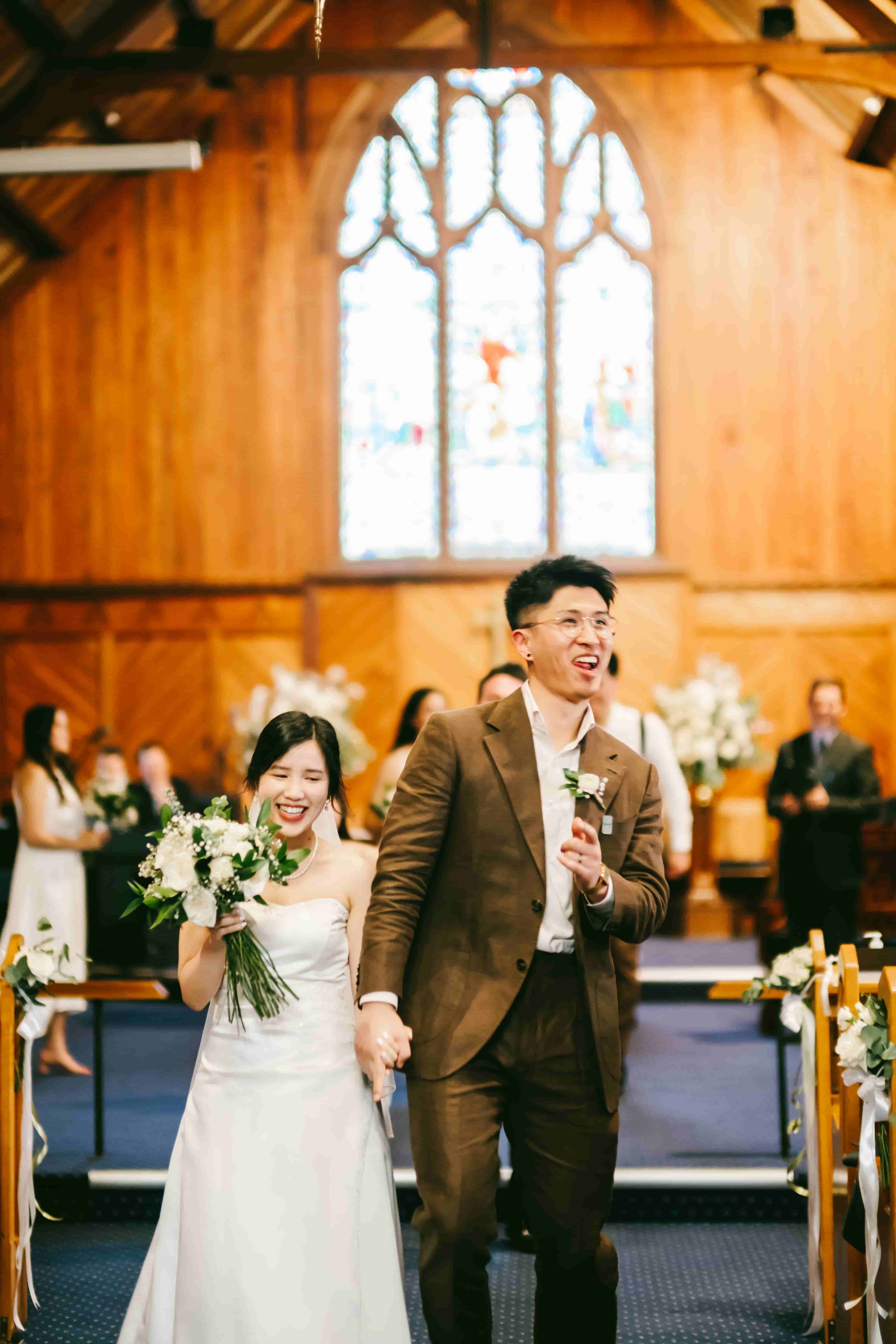 May and Sam beaming as they walk back up the aisle hand in hand as a married couple