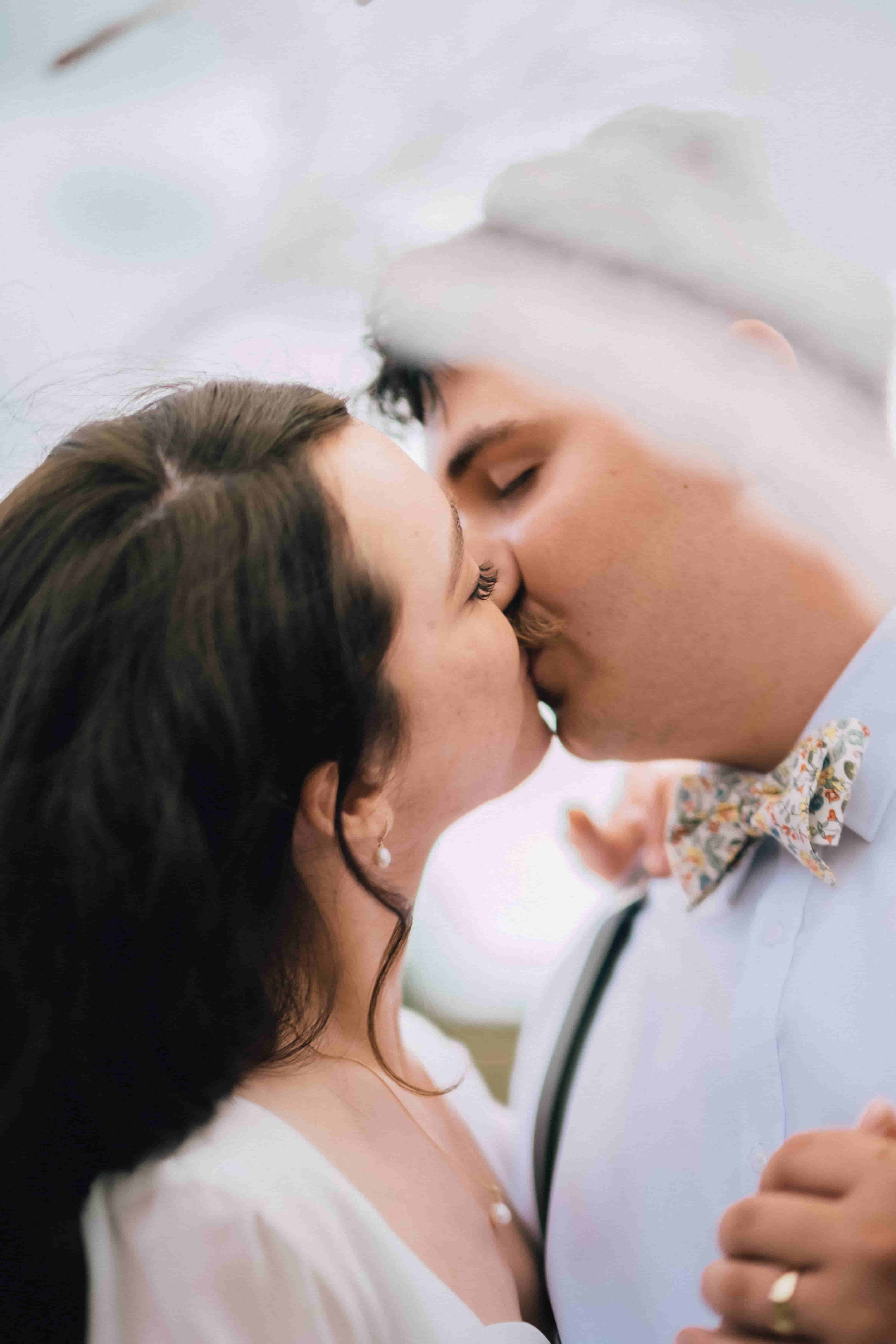 Joe kissing Mia through a soft blur of lace, his floral bow tie in view