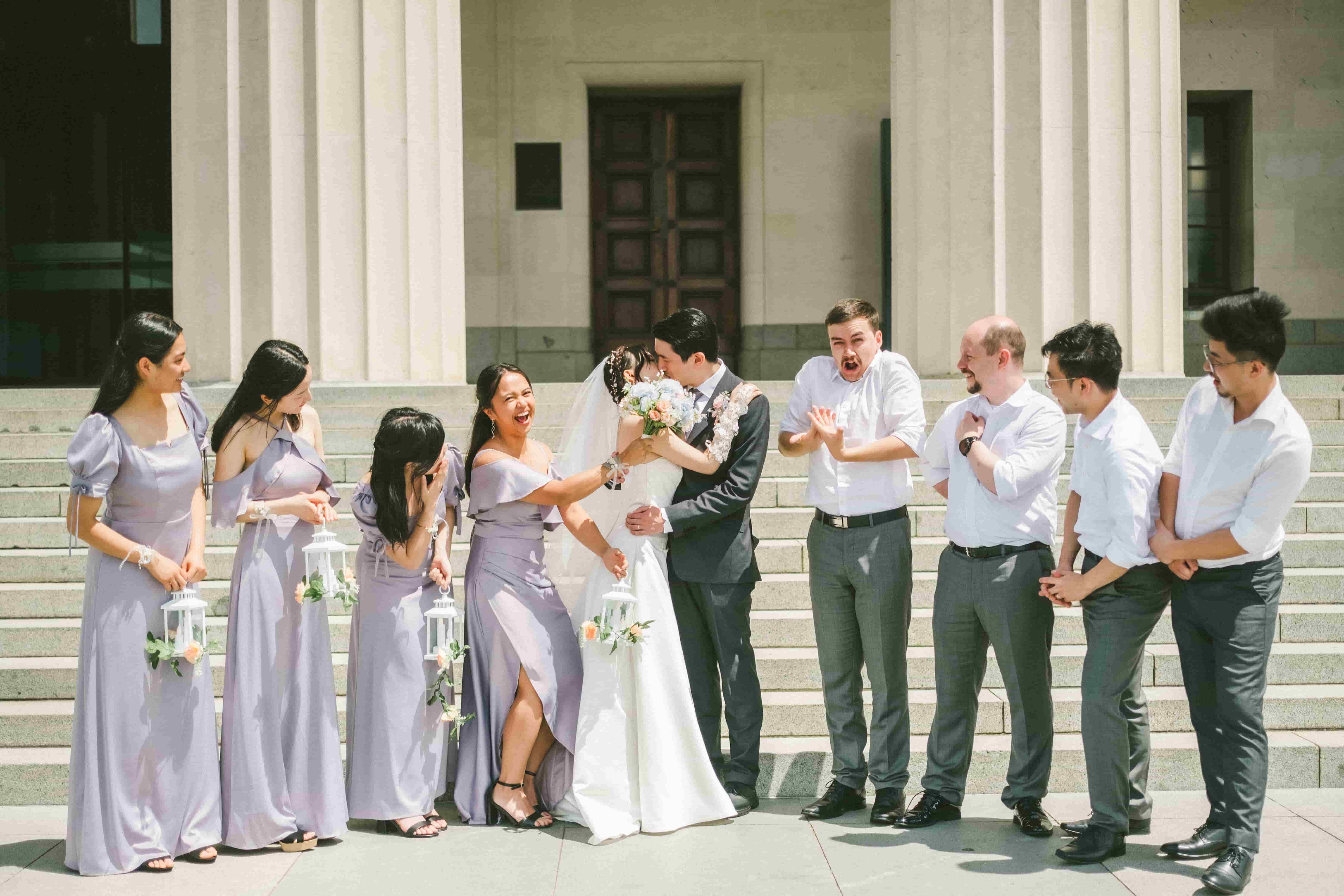 Hans and Chrystynn laughing with their bridal party on the steps of a columned building
