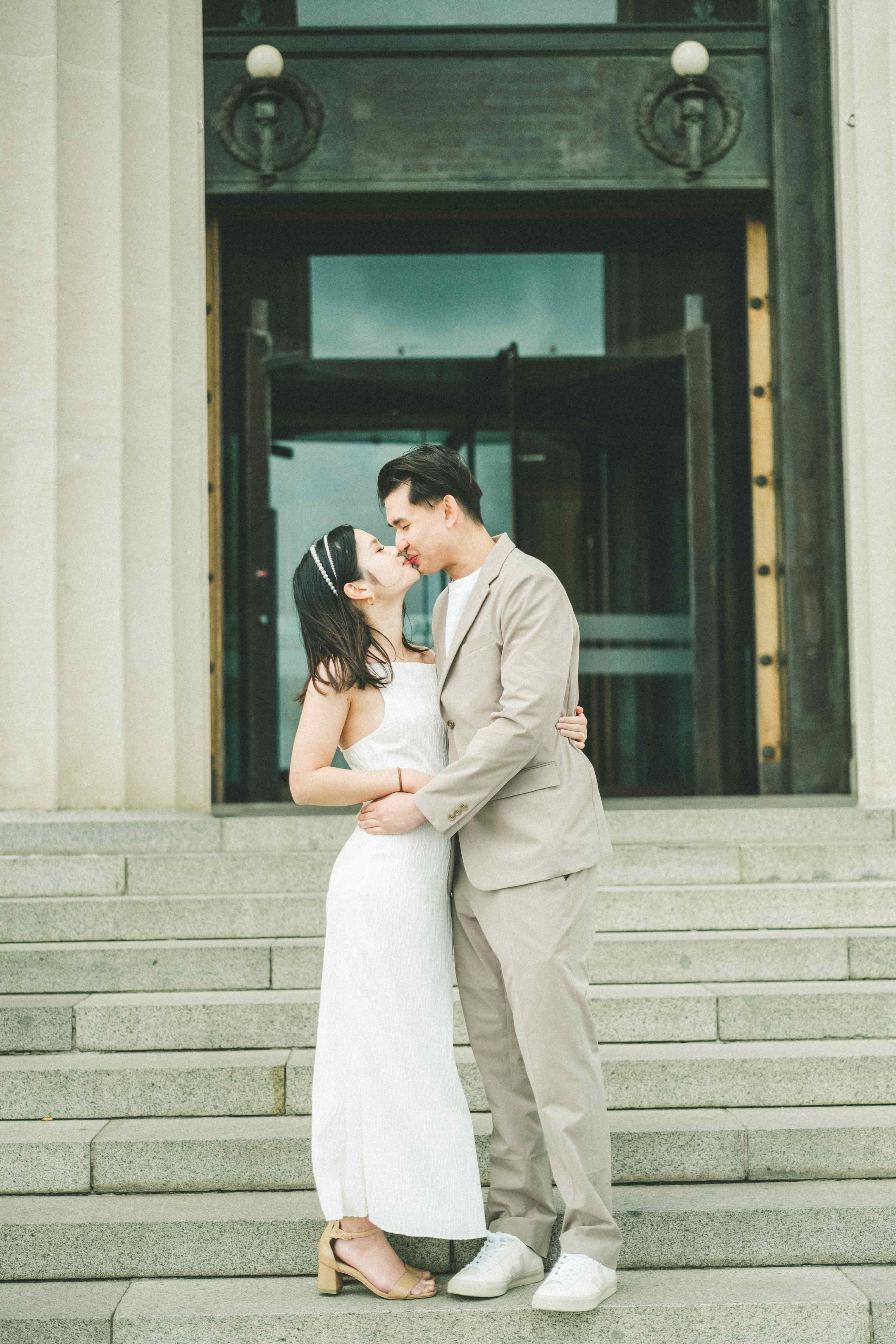 Suzen and Nick sharing a kiss on wide stone steps in front of a tall doorway