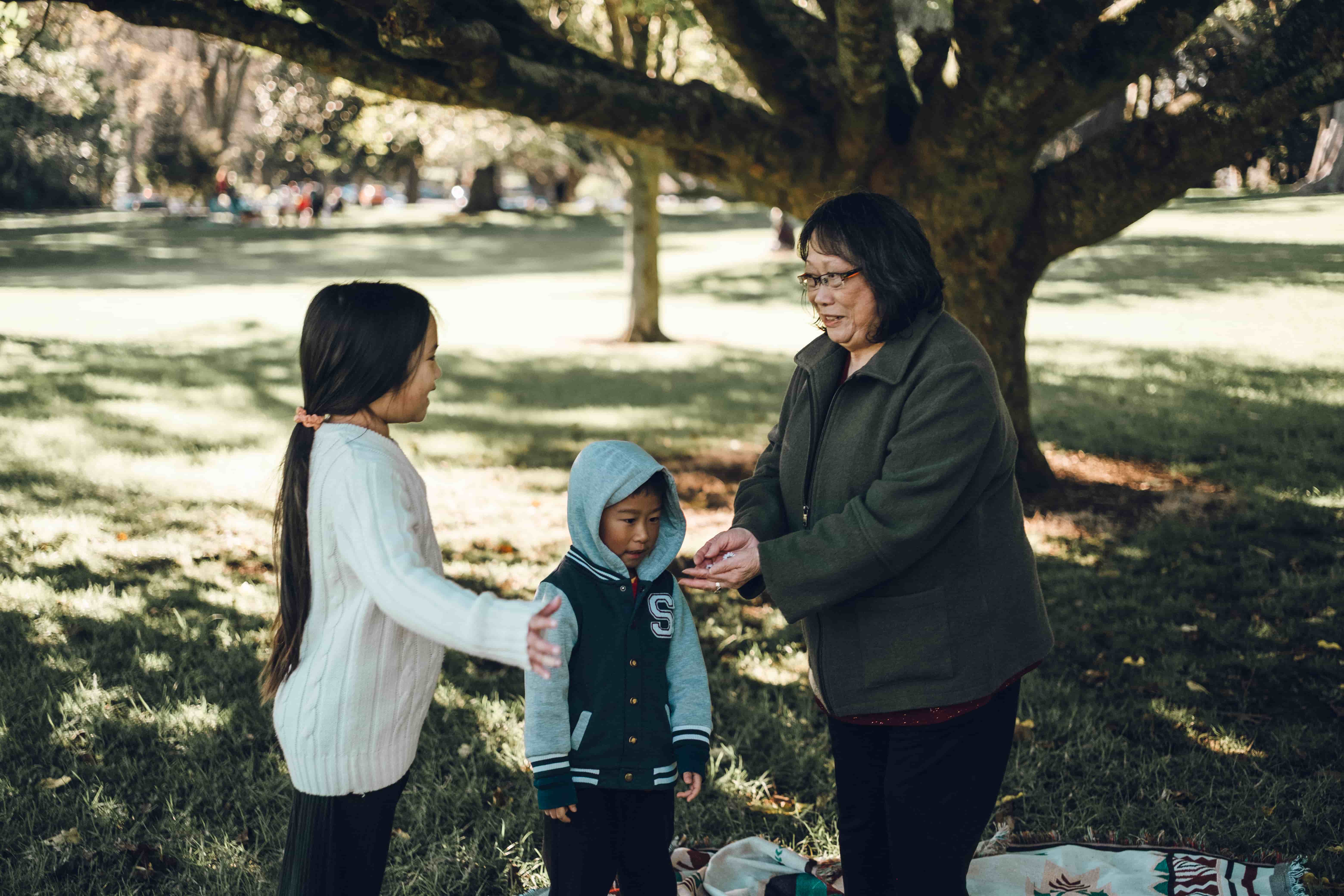 Grandmother holding hands with two grandchildren on the lawn