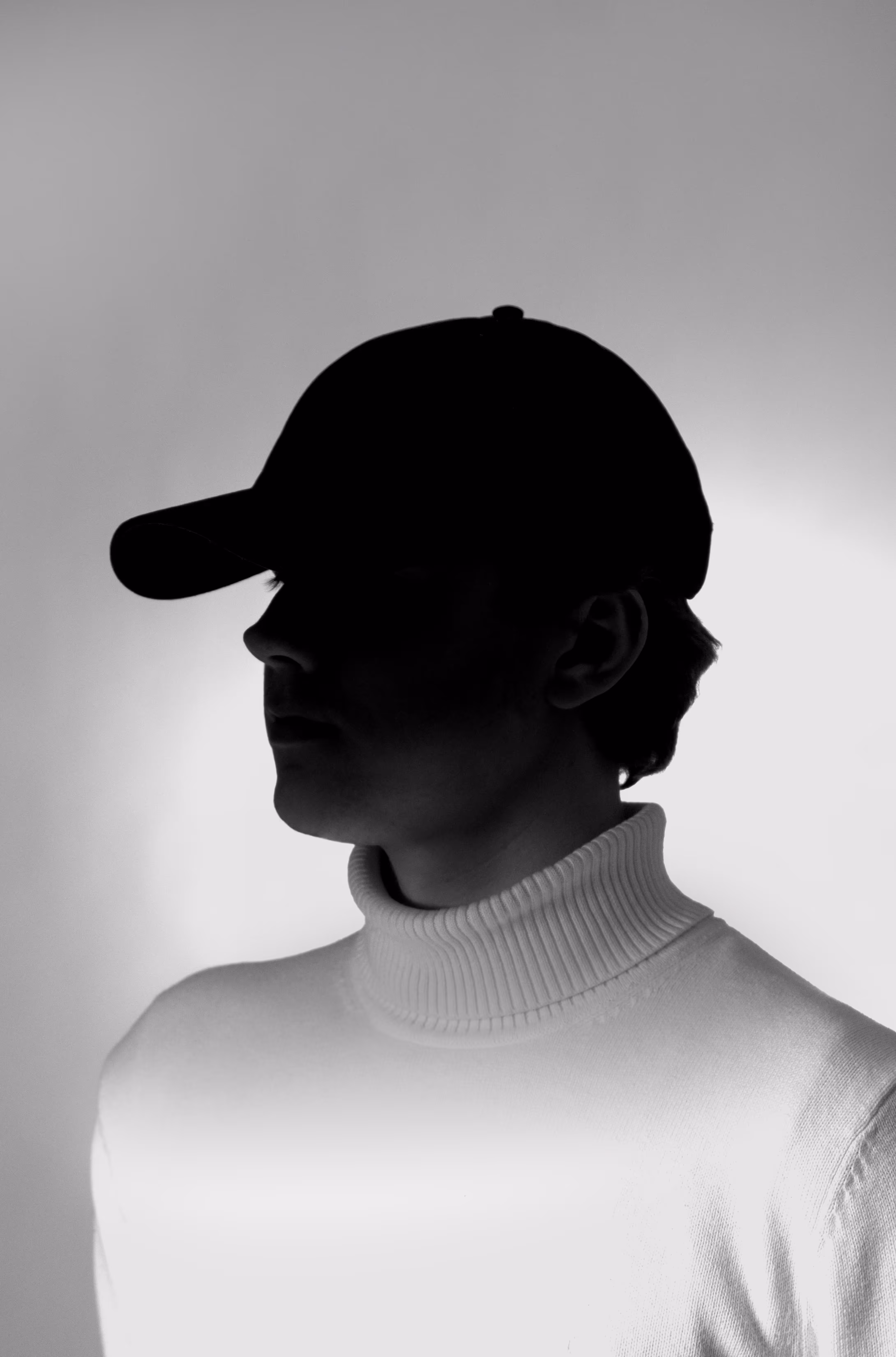 Portrait einer Person vor einem grauen Hintergrund mit einem starken Schatten im Gesicht