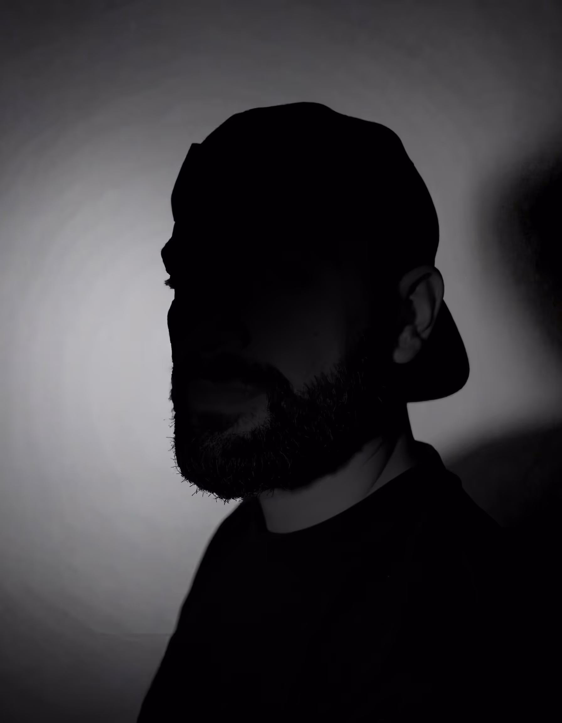 Portrait einer Person vor einem grauen Hintergrund mit einem starken Schatten im Gesicht
