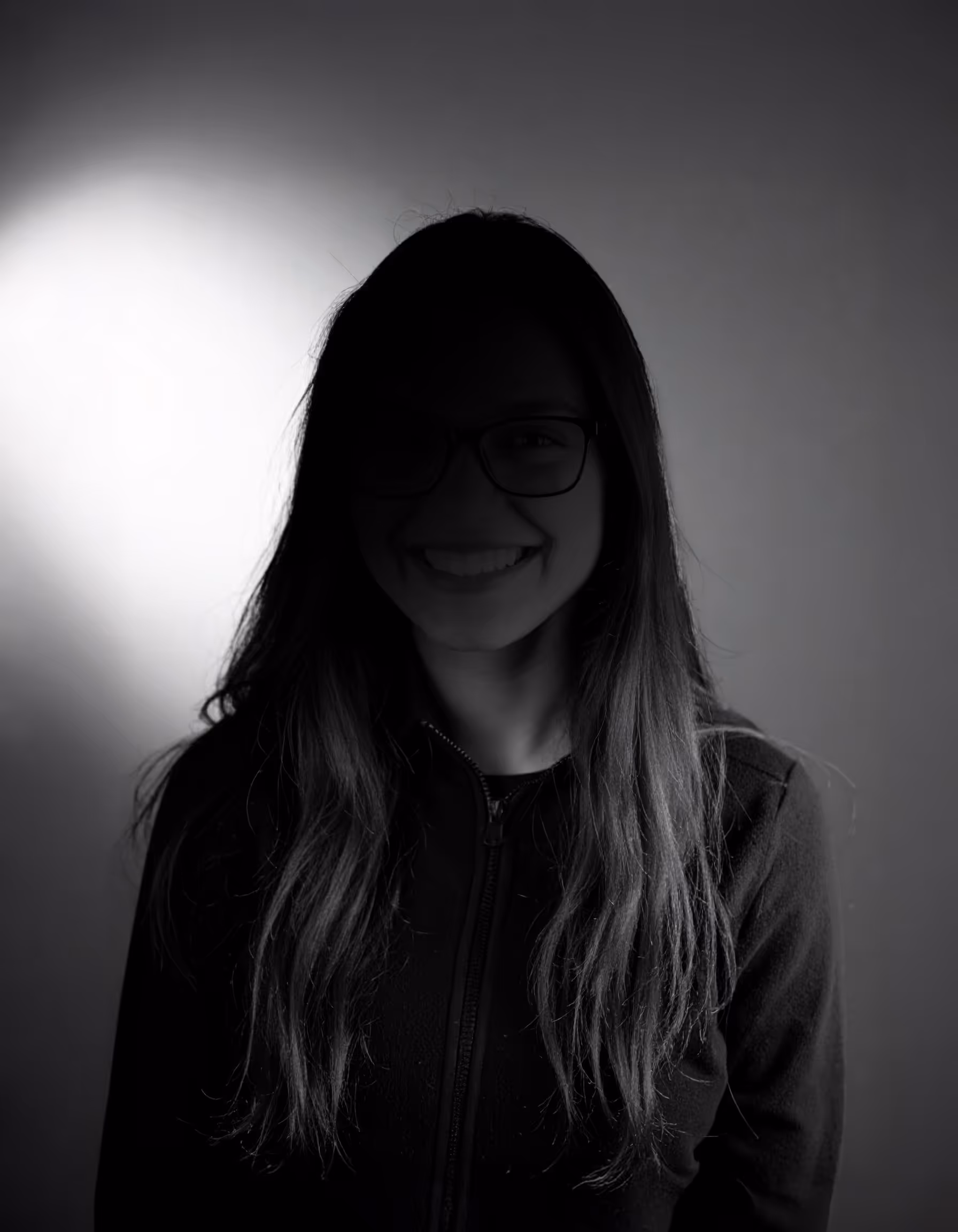 Portrait einer Person vor einem grauen Hintergrund mit einem starken Schatten im Gesicht