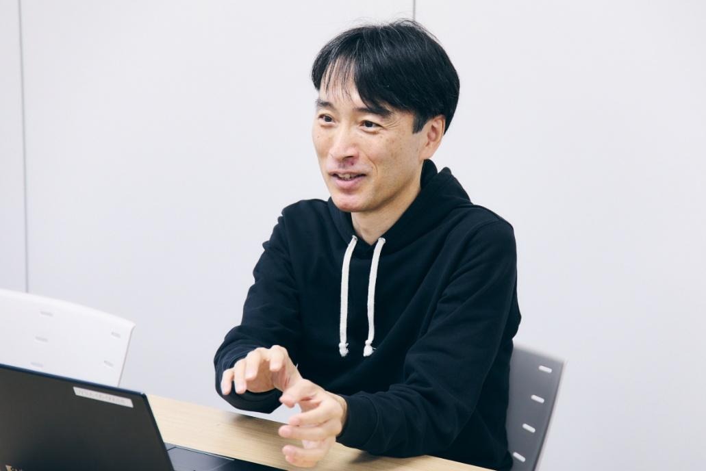 机の上に座っている男性中程度の精度で自動的に生成された説明