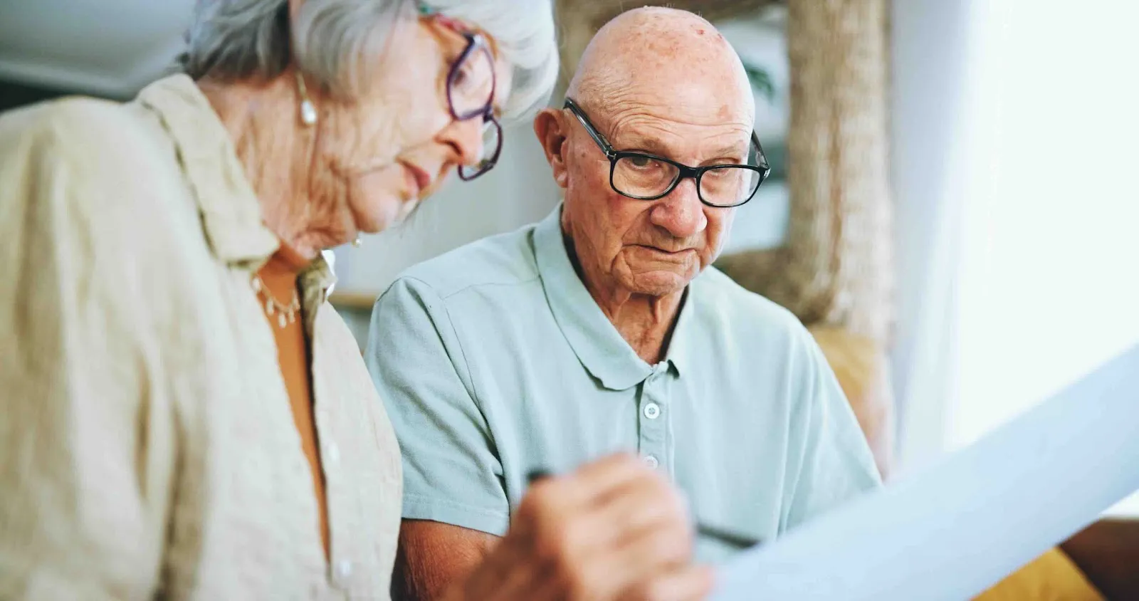 Senior couple reviewing end-of-life planning documents together at home, preparing their advance directive and living trust to ensure their end-of-life legal documents are in order.