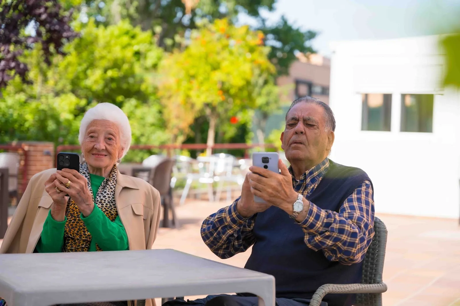 Two older adults using smartphones outdoors, exploring the best calendar apps and shared calendar apps designed for caregivers and families.