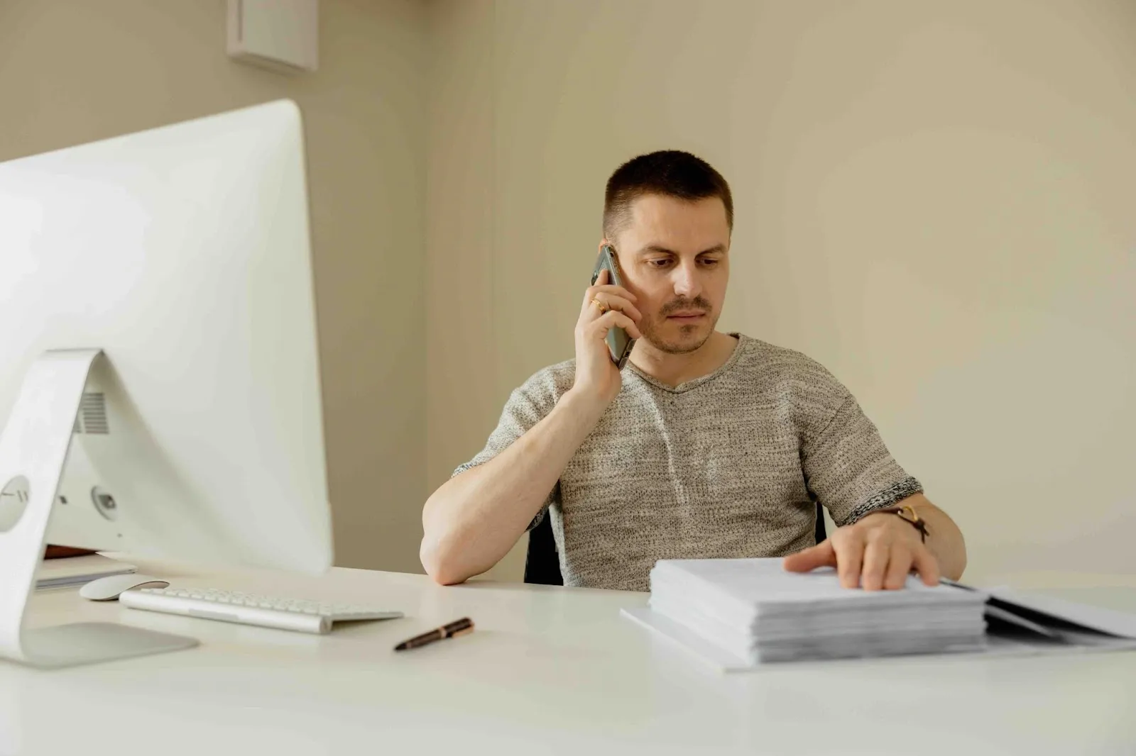 Man on the phone at his desk reviewing paperwork, possibly managing subscription cancellation after death or closing accounts after death