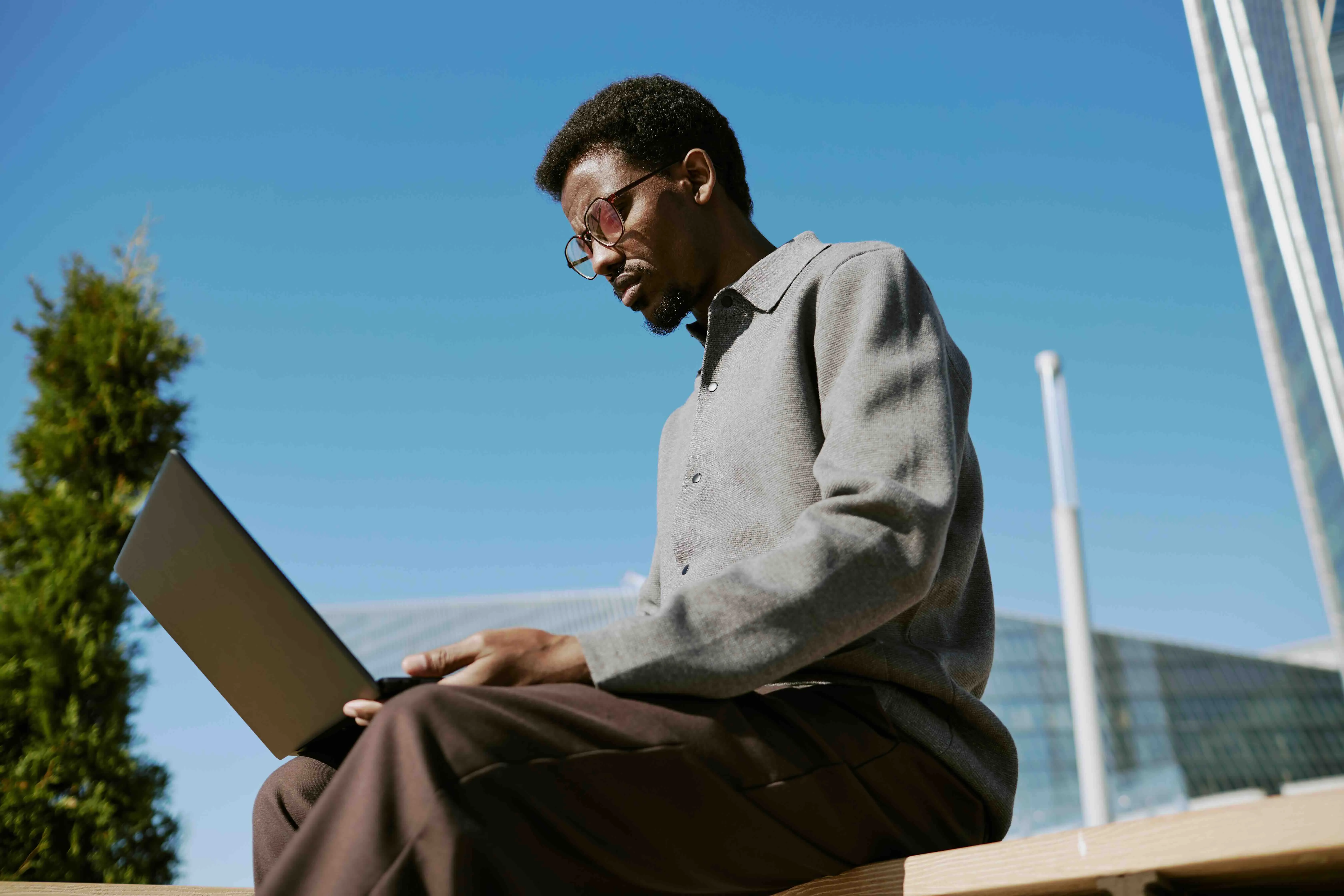 Working caregiver using a laptop outdoors, balancing work and caregiving responsibilities while managing tasks remotely.