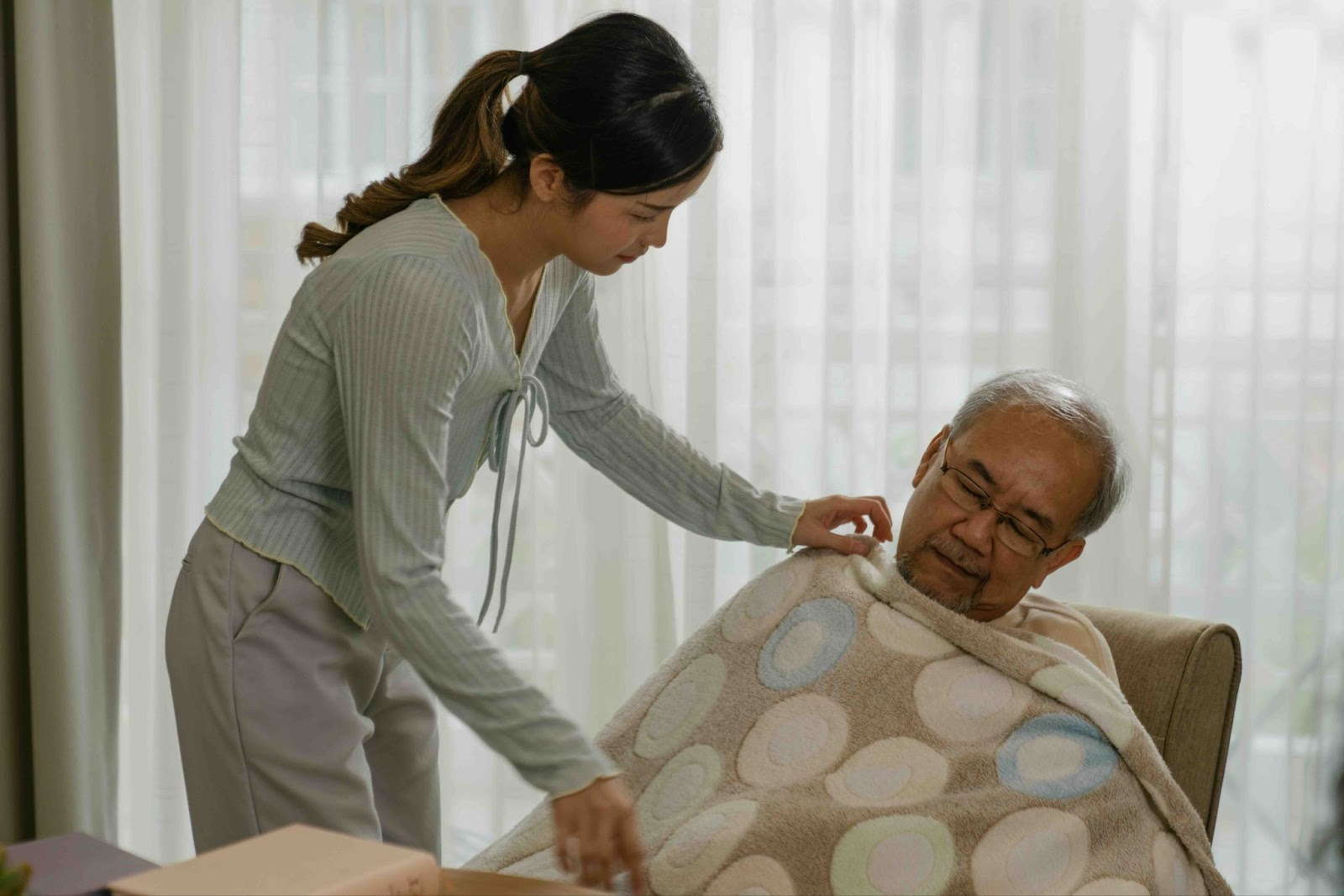 Young woman caring for her elderly father at home, showing the role of working caregivers balancing family caregiving while employed.