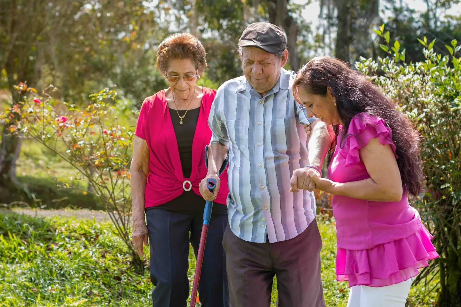 : An elderly couple walks outdoors with the support of their adult daughter, representing family caregiving, empathy, and workplace support for caregivers. This image highlights the importance of a positive work environment and employee retention strategies that recognize caregiving responsibilities.