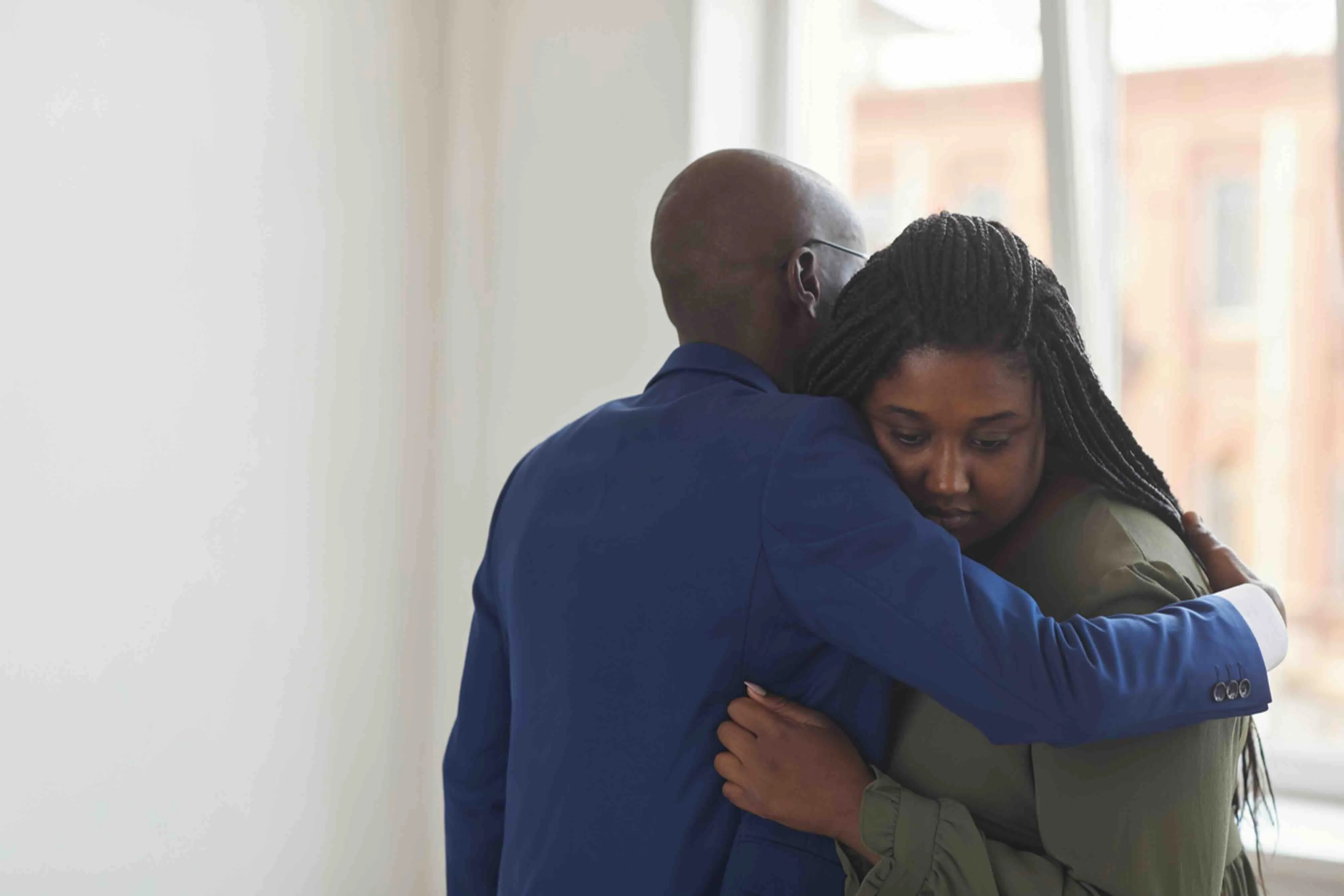 Two people embrace indoors, offering grief support during a difficult moment, symbolizing how to support someone in grief and what to say to a grieving friend.