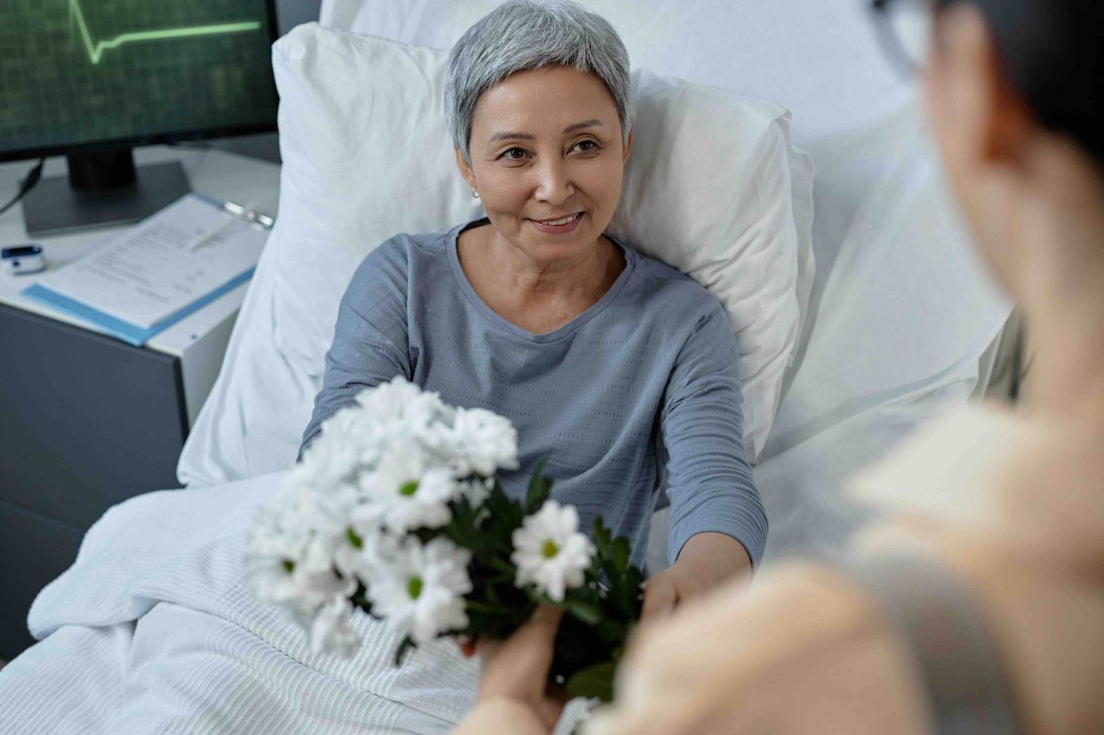Caregiver for breast cancer patient offering flowers in the hospital, showing kindness, support, and emotional care during chemo treatment